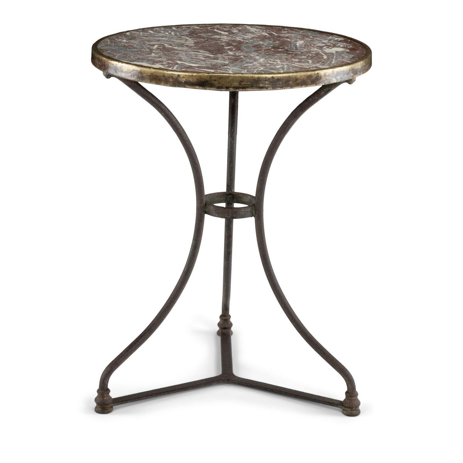 Red marble top French bistro table circa 1890-1909. Round marble top in rouge, gray and white veins, secured in place with a gilded steel rim, atop a forged iron base.