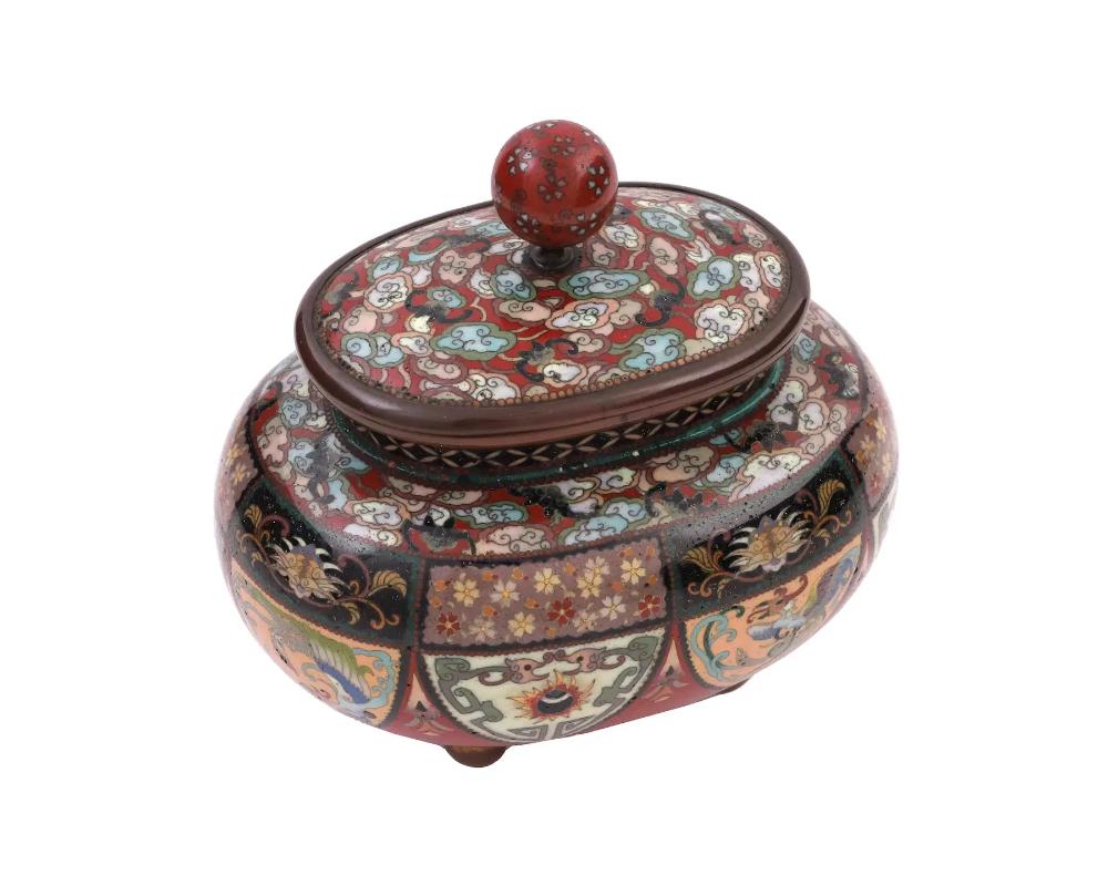 An antique Japanese copper covered jar or box with polychrome cloisonne enamel design. Late Meiji period,Squat rounded piece resting on four ball feet. Richly decorated with floral and animal patterns, red color palette. Globe finial on top of the