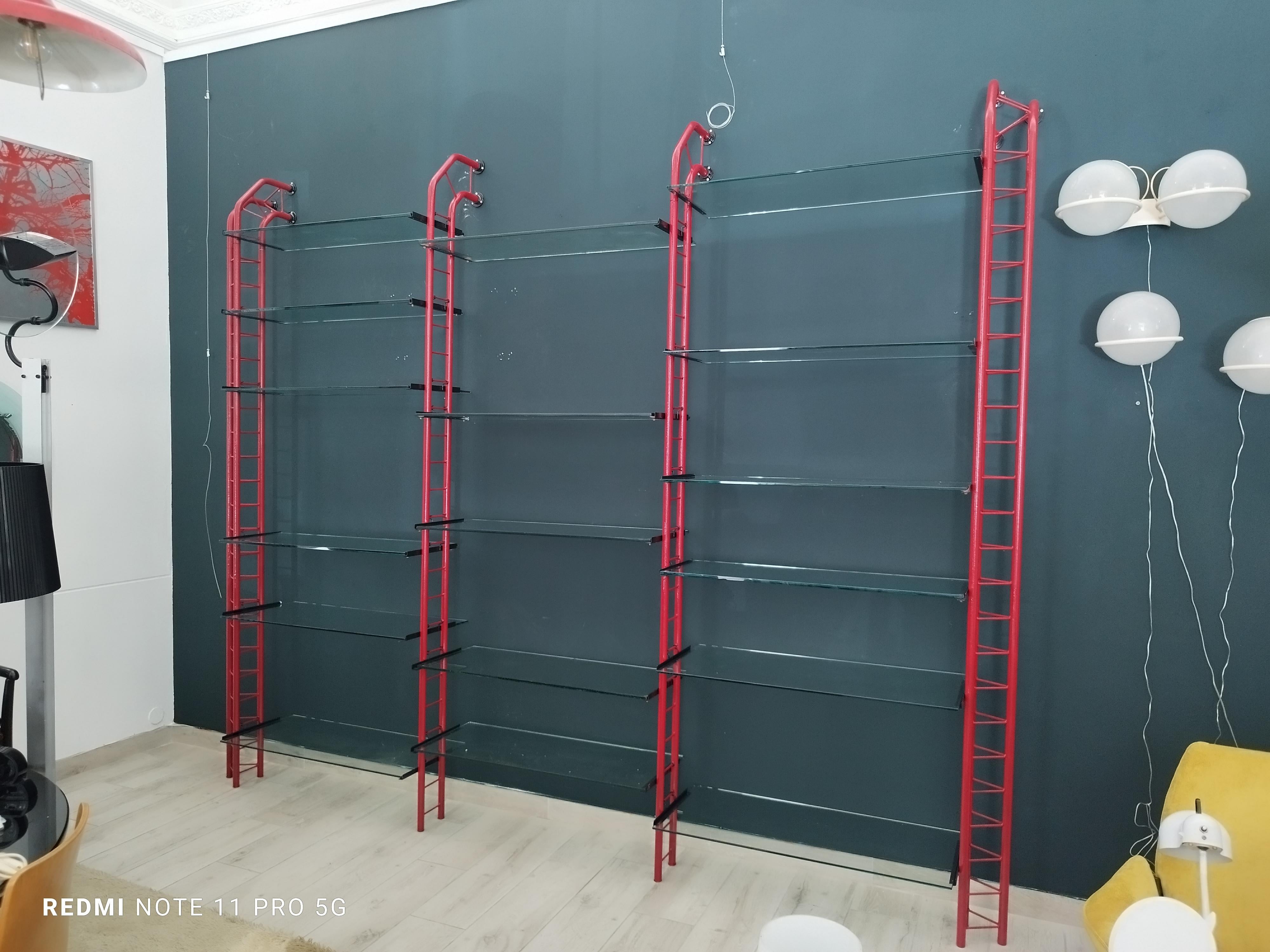 
Librería industrial modernista memphis años 80 de metal pintado de rojo y 17 estantes de cristal, al estilo de Paolo Piva.