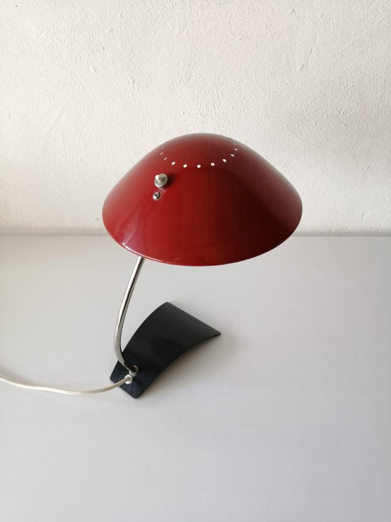 Metal table lamp model 6840 by Christian Dell for Kaiser Leuchten, 1960s

Exceptional Bauhaus design.
Very high quality. Black base and red head of the lamp made of metal. 

With the row of holes on the lamp head, there is also a pleasant light