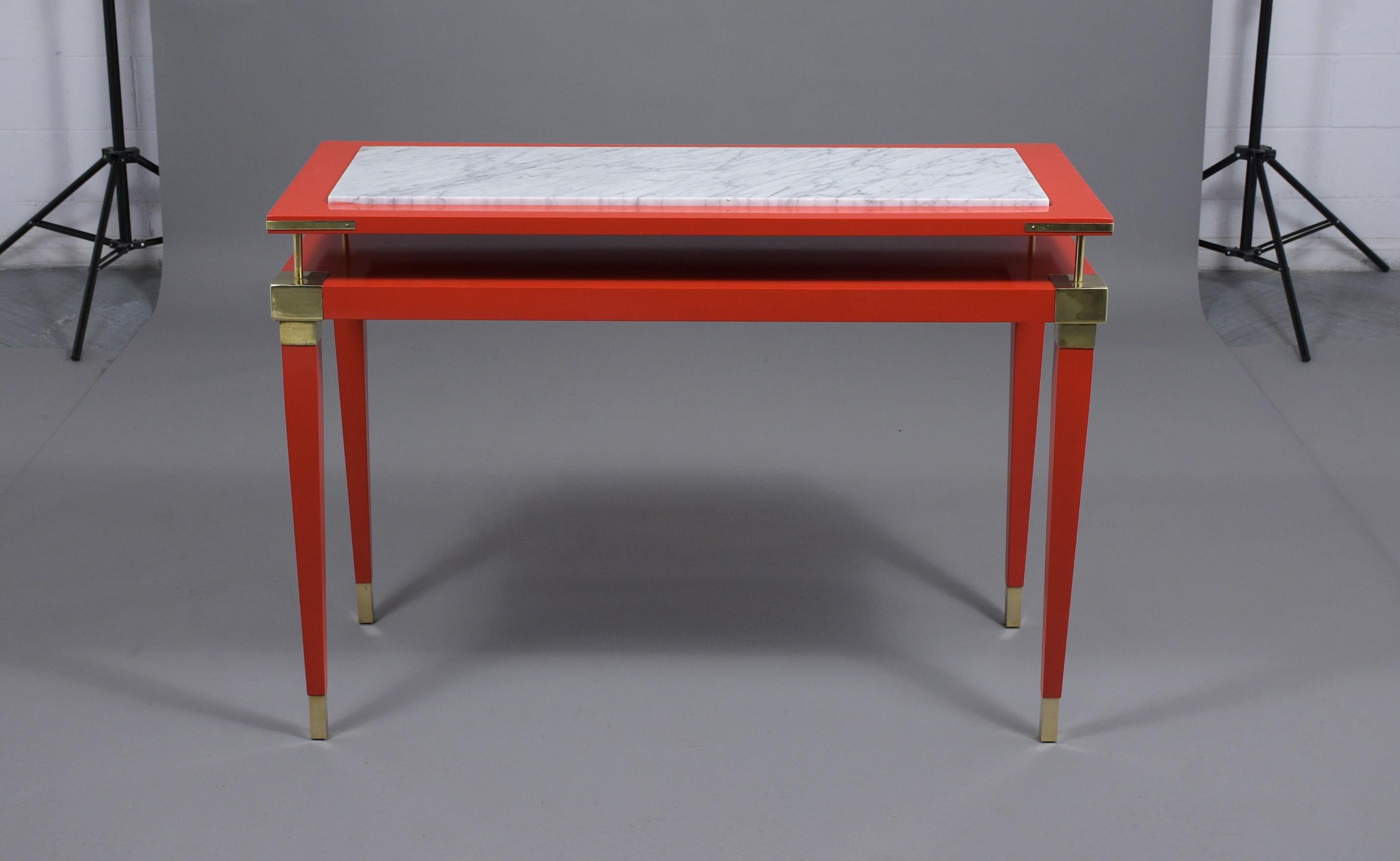 A 1970s vintage Maison Jansen style sofa table hand-crafted out of wood that features a beautiful red lacquered finish. This unique console has the tabletop floating above the base by simple, but sturdy brass poles, and the top of the table has a