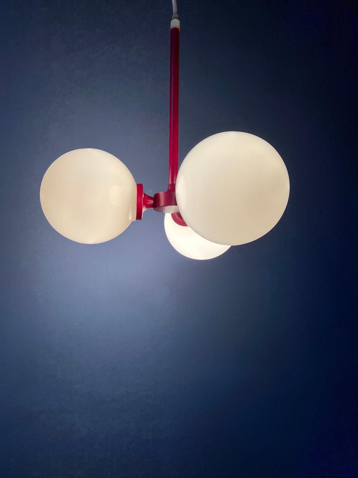 Lampadario in vetro di metà secolo con struttura rossa e tre paralumi in vetro opalino. La lampada richiede tre lampadine E14.

Informazioni aggiuntive:
Materiali: Vetro, metallo
Periodo: 1970s
Dimensioni: ø Paralume completo della lampada: 38