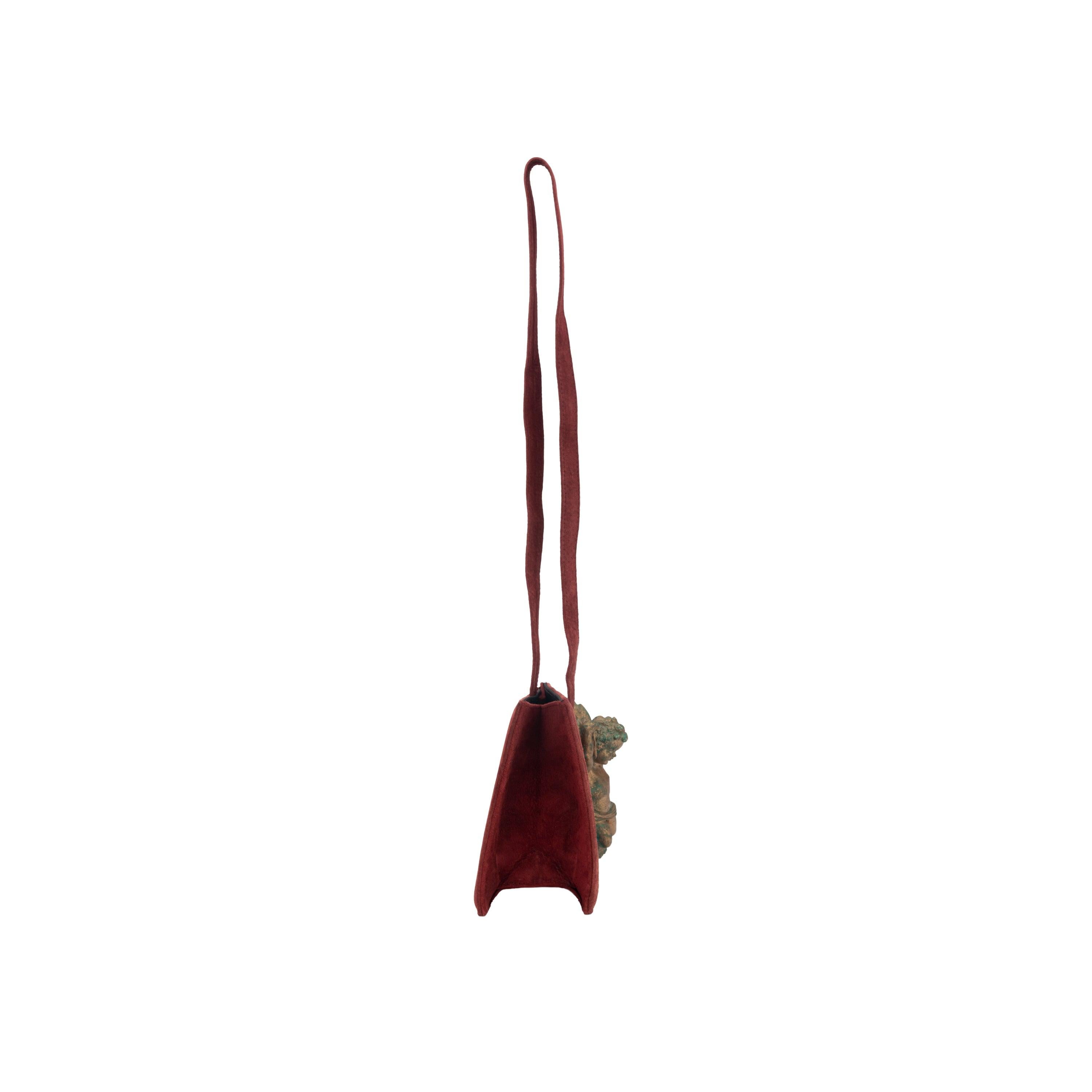 31 FÉVRIER mini borsa in pelle scamosciata rossa. Tracolla, chiusura con bottone a pressione, decorata con un putto in legno dorato. Altezza:15; Larghezza:15; Profondità:9;