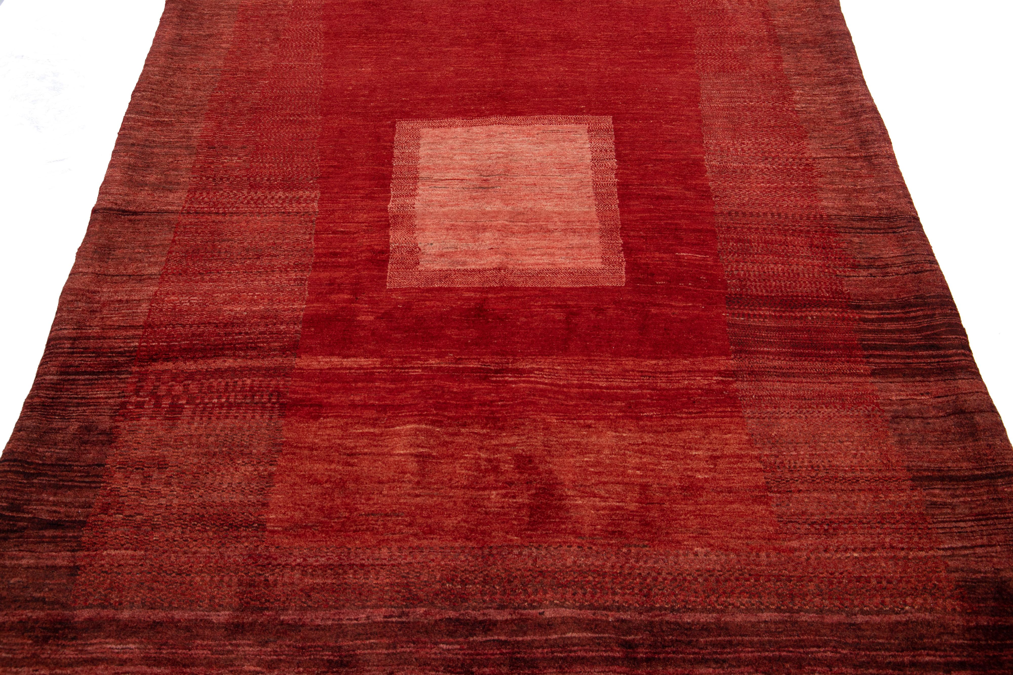 Schöner, moderner, handgewebter Wollteppich im Gabbeh-Stil mit einem roten Farbfeld. Dieser Perserteppich hat ein wunderschönes minimalistisches Design mit hellroten Akzenten.

Dieser Teppich misst: 4'11