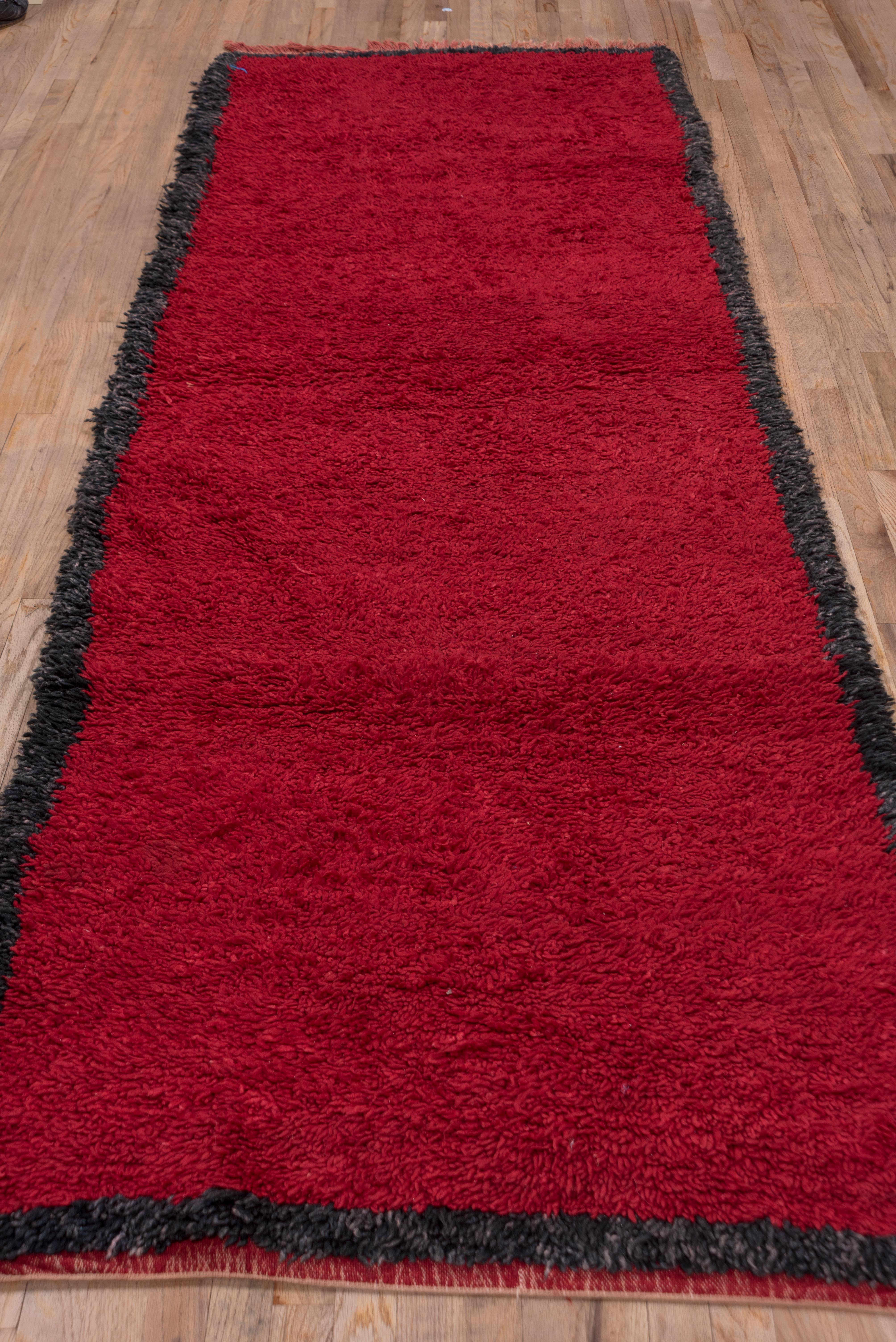 Thick hand-knotted wool made in Morocco in the early to mid twentieth century, this red with black trim piece is a perfect statement to any hallway or water closet. 