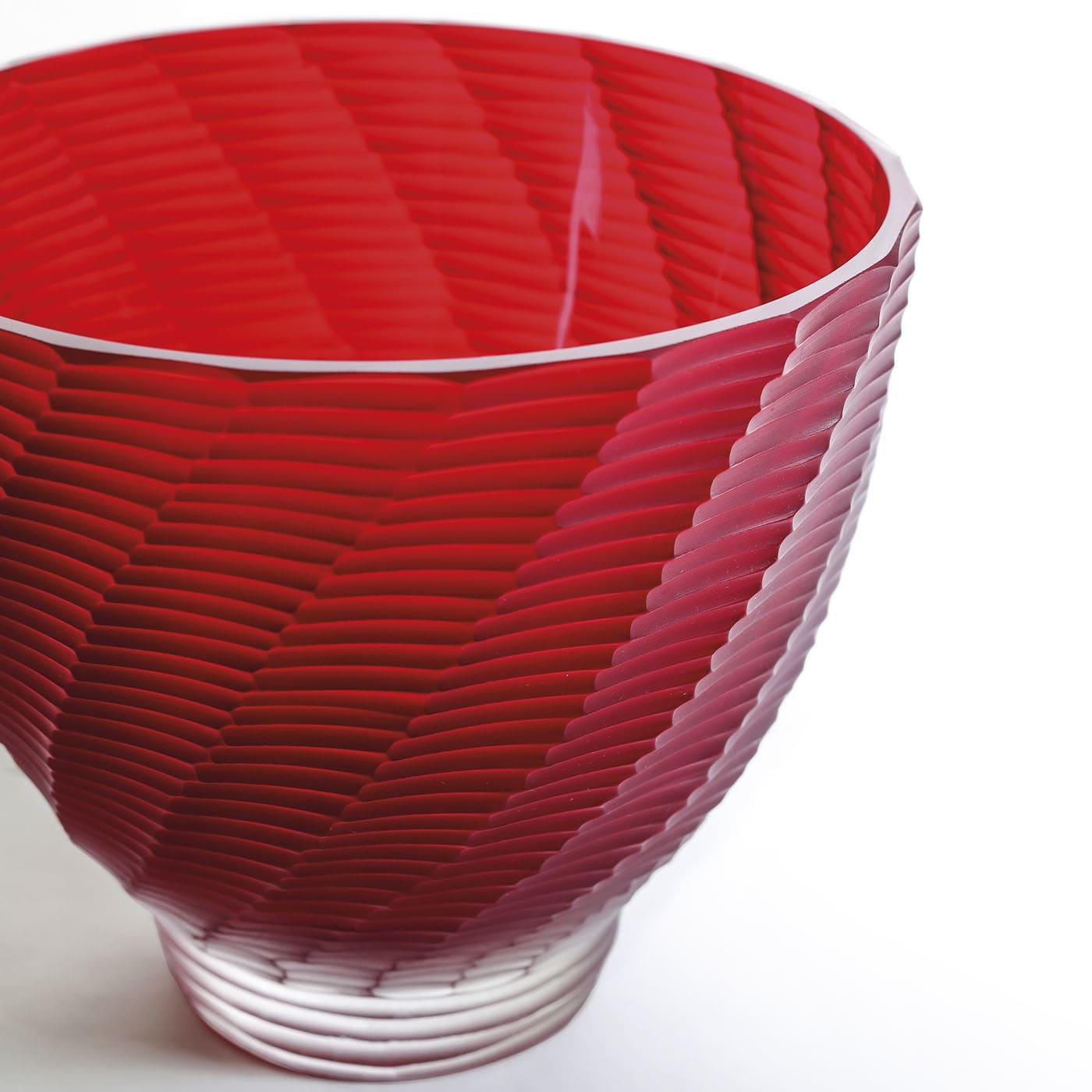 A painstaking process of manual grinding is behind the twisted texture of segments extensively characterizing this precious bowl. Crafted from mouth-blown red Murano glass and indeed unique, it also showcases an intriguing contrast of finishes