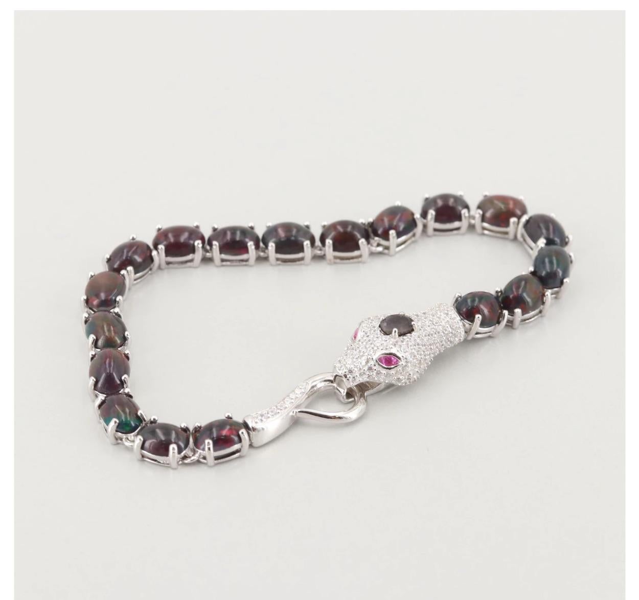 A beautiful exotic Sterling Silver Gemstone Bracelet with Red Cabochon Opals, an oval Sapphire on the Snake Pave Diamond Head, with Red Stone Eyes.
15 CTW Red opal gem bracelet, diamond pave head with an oval .24 carat Sapphire center and two