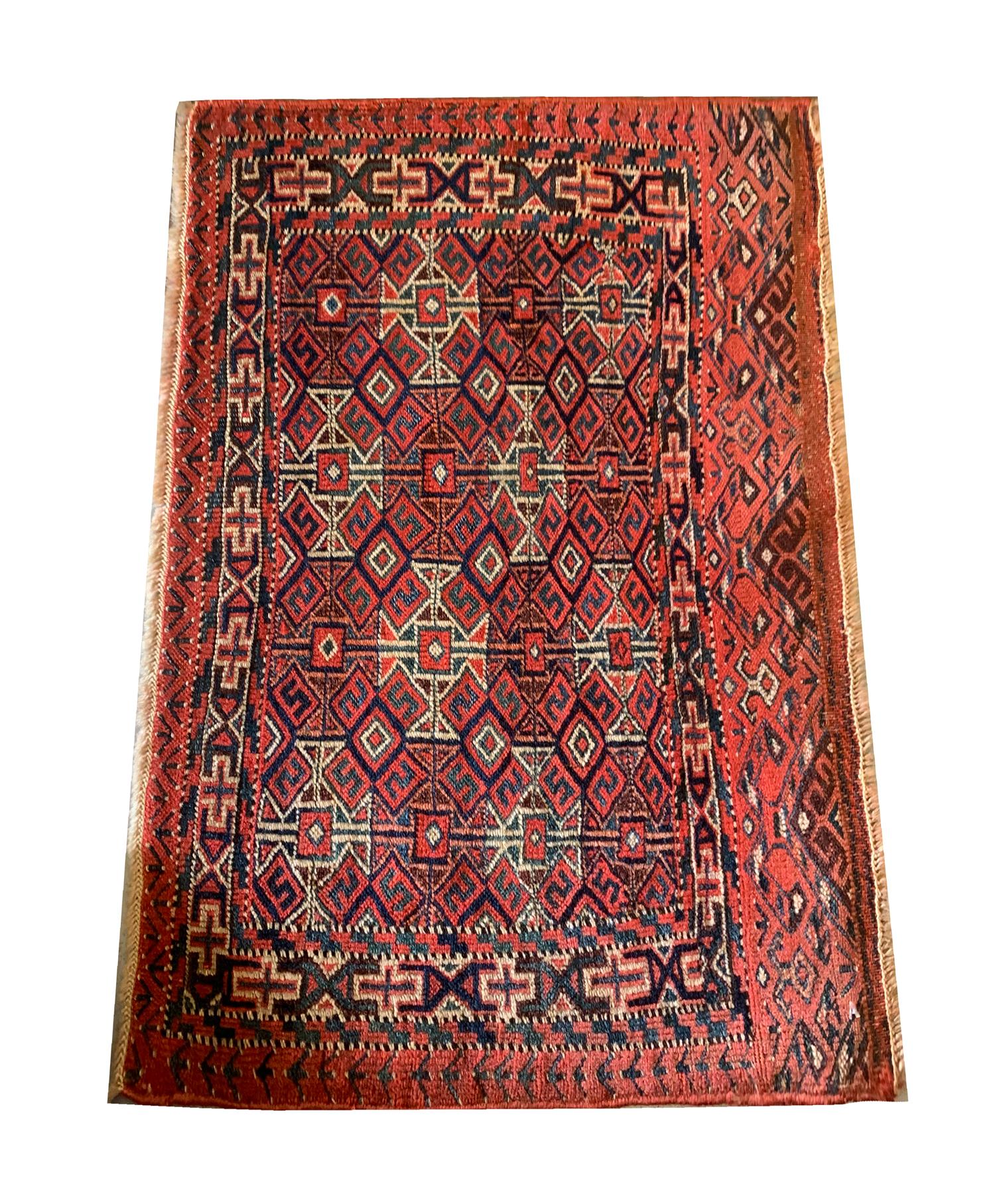 This fine wool rug was woven by hand in the 1890sTurkmens. This piece features a rich red background with brown, cream, beige and green accent colours woven in a symmetrical geometric pattern, traditional in tribal village rugs. A layered repeat