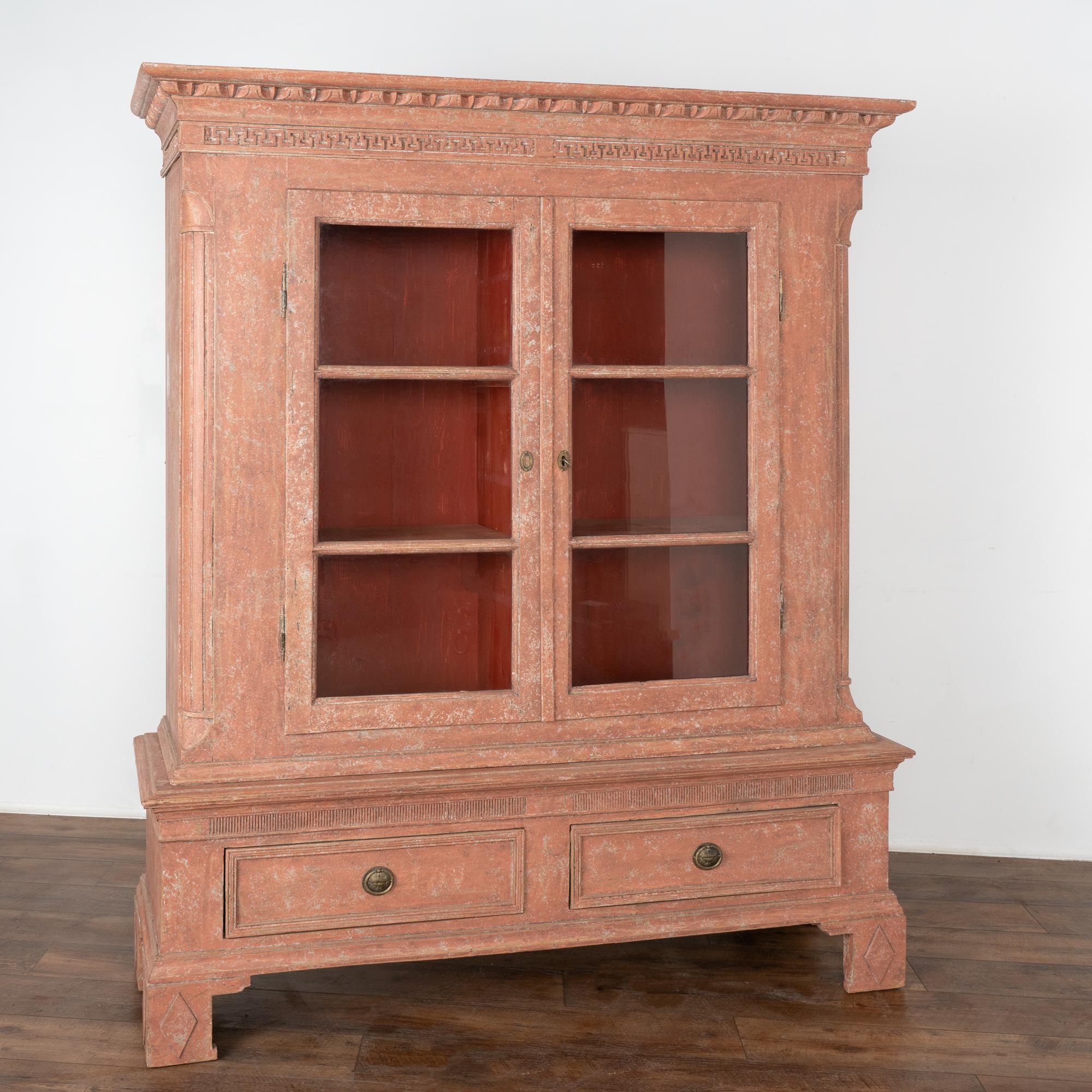 The details in this large red Gustavian pine bookcase are impressive with carved molding and Greek key pattern along the crown, carved inset columns at side and fluted carved details along base. 
The upper glass doors allow for beautiful display of