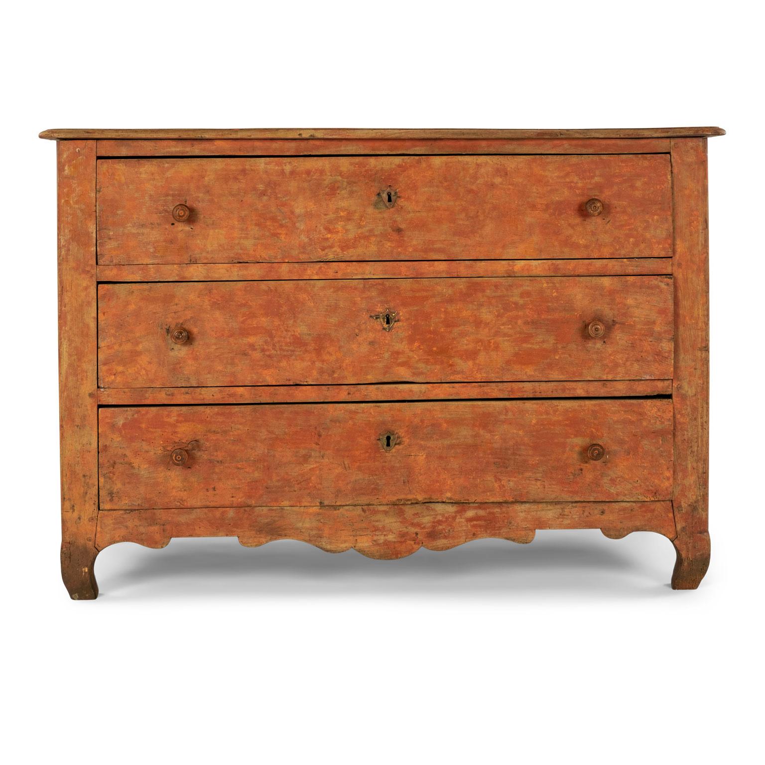Orange painted rococo commode dating to the mid-18th century. Three-drawer commode with turned knob pulls. Scraped back to original orange paint. Excellent condition. Sturdy and stable. Mortise and tenon joints are newly tightened. Dovetailed