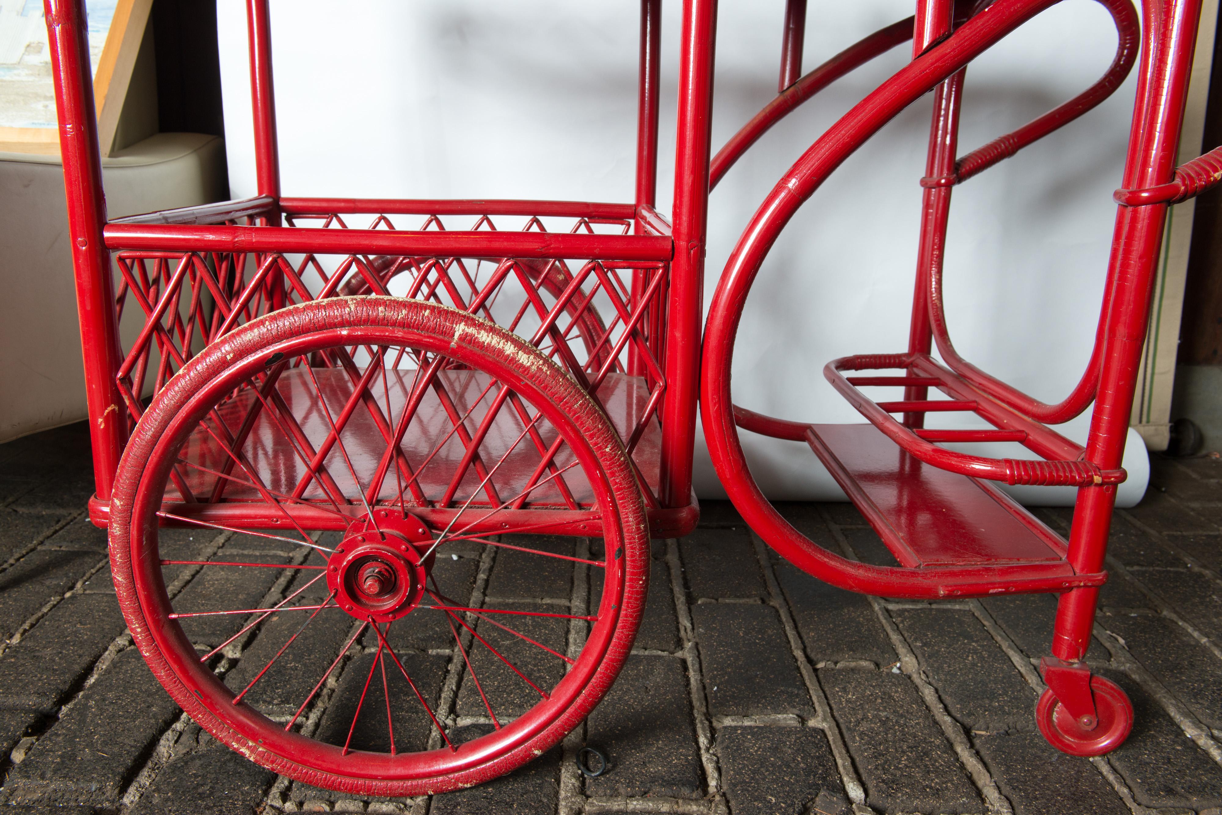Red painted rattan bar cart with two big wheels, great form. Two levels and a platform for four bottles. 
Lot of look! Top surface is 17 x 31 x 28 high.