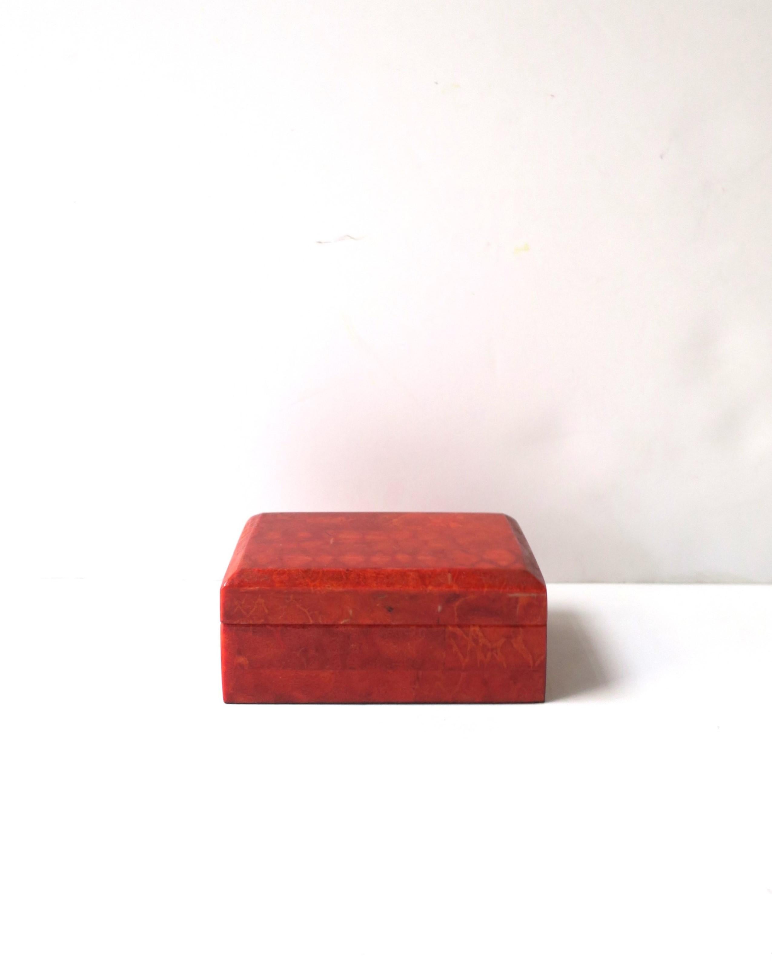 A small red resin laminate over wood jewelry box. A convenient box for holding jewelry (as demonstrated) or other small items on desk, vanity, bedside table, dresser, on top of books, etc. Many uses. A great red hue offering a pop of color to any