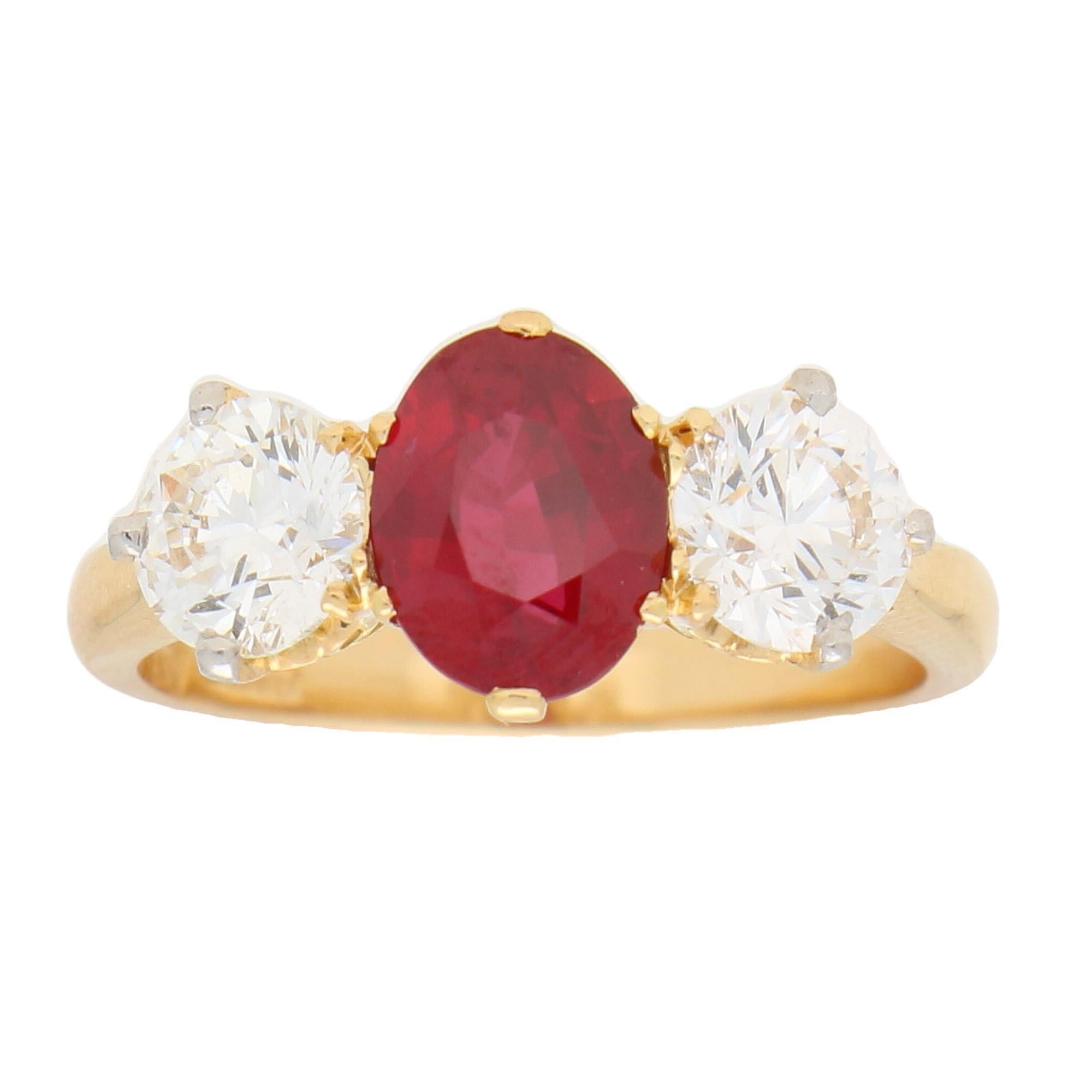 A beautiful vibrant red ruby and diamond trilogy engagement ring set in 18k yellow gold.

This classic design of engagement ring is centrally six-claw set with an oval cut ruby which is a beautiful vibrant red colour. This ruby is then sided by two