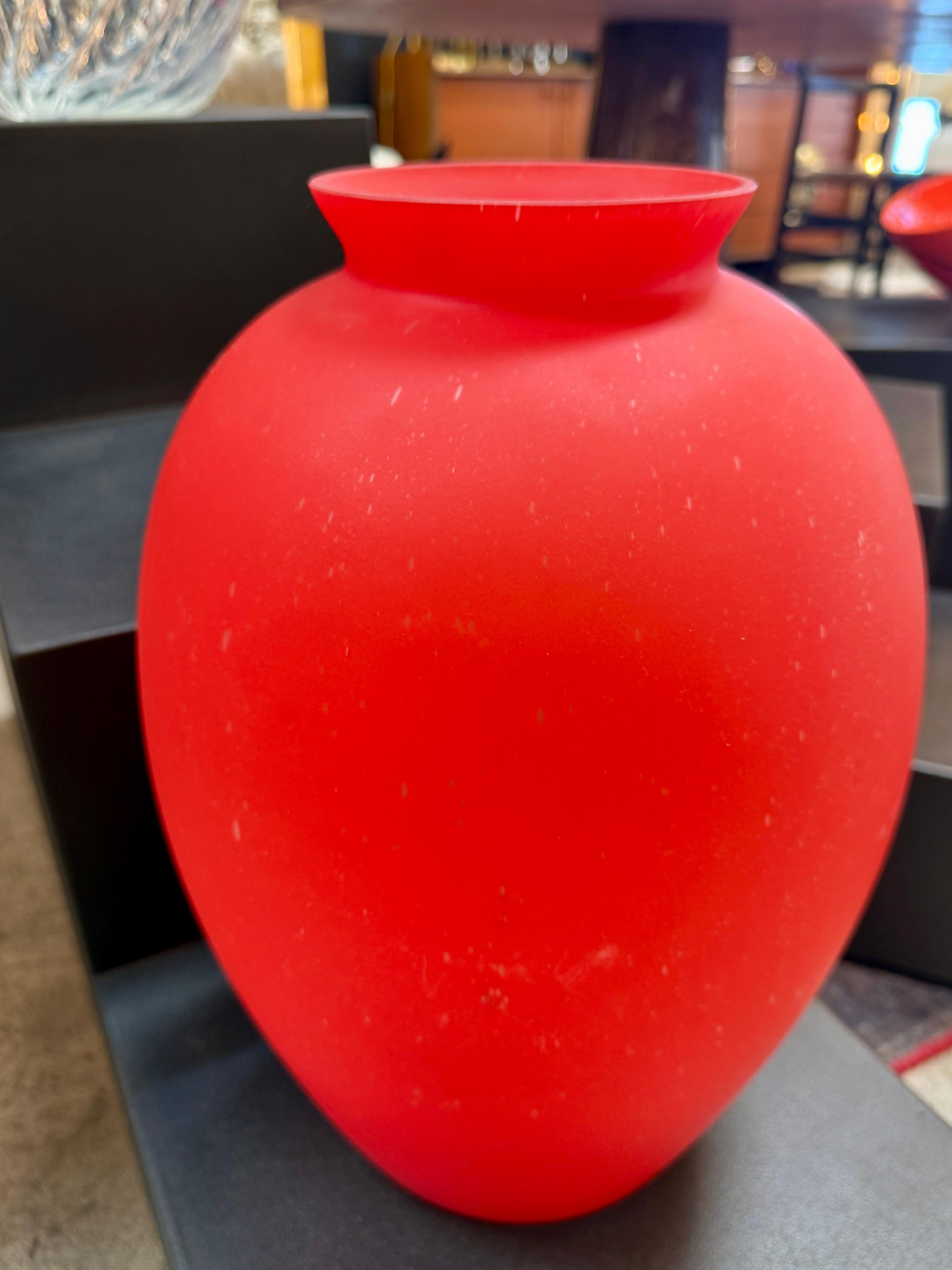 Ce vase audacieux et élégant met en valeur l'art intemporel de la verrerie italienne. Fabriqué dans une finition rouge satiné saisissante, le verre soufflé à la main présente une surface lisse et mate qui contraste magnifiquement avec sa silhouette