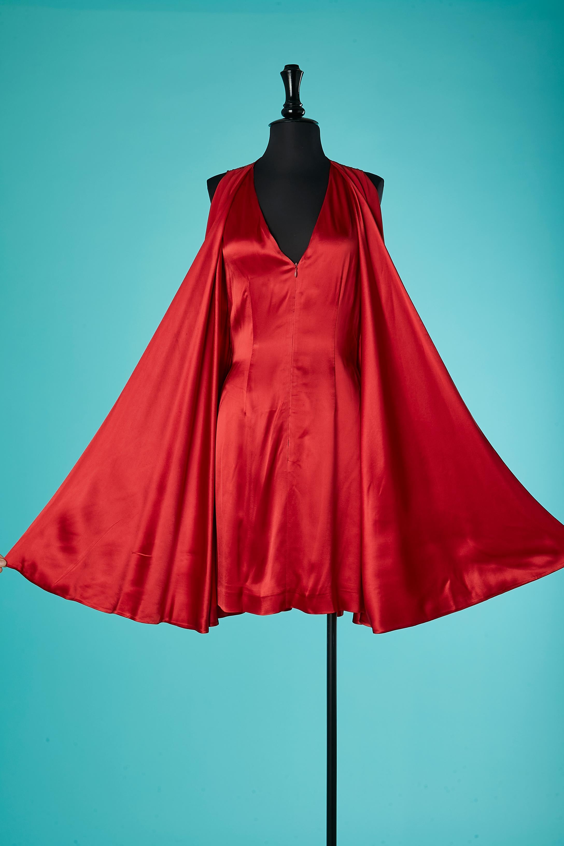 Robe de cocktail sans manches en satin rouge avec dos en dentelle transparente et effet cape. 
Pas d'étiquette de composition du tissu mais probablement du satin de soie . Un côté est brillant (la robe) et l'autre est mat (la cape est mat).