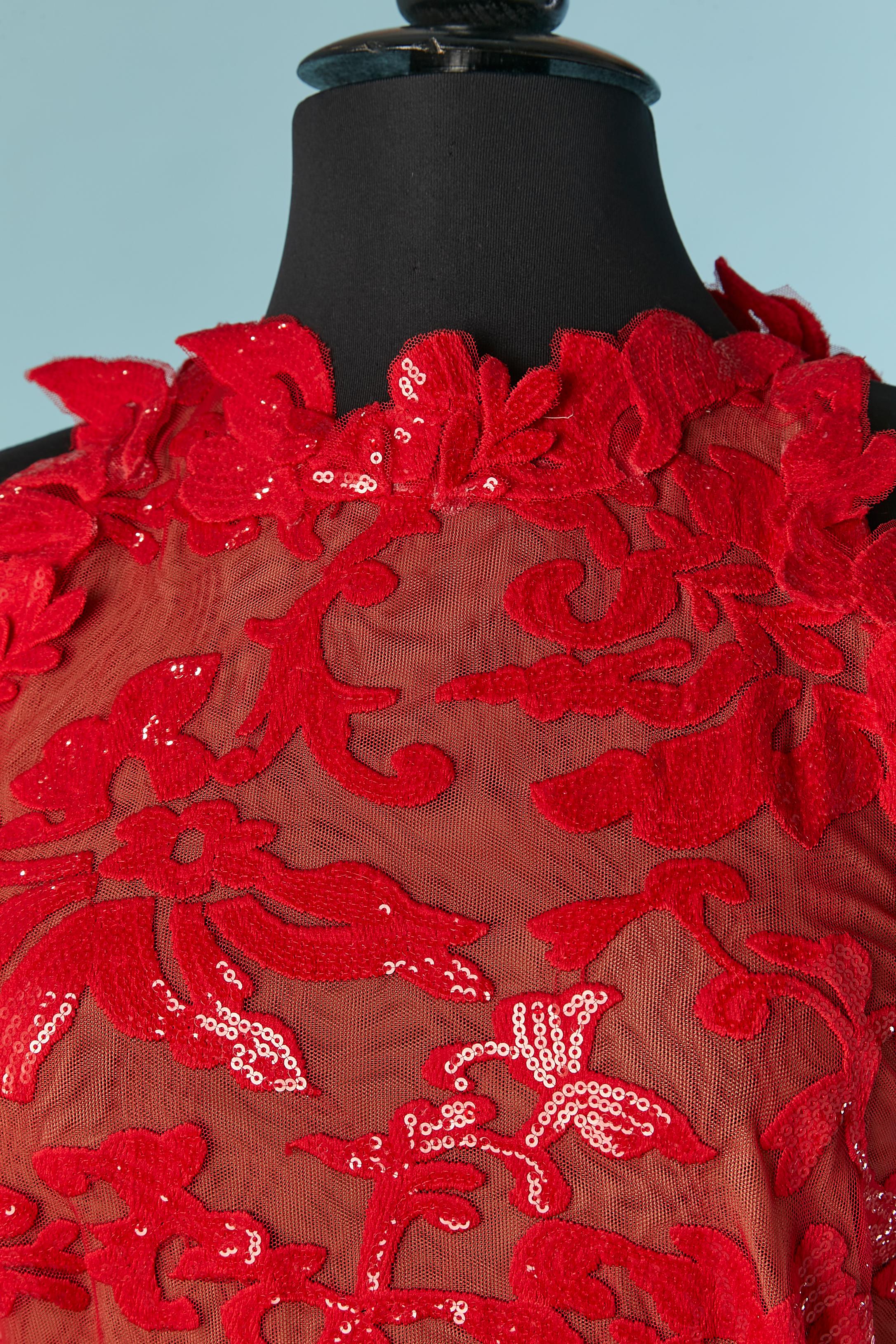 Vestido de noche bordado de lentejuelas rojas con sobrefalda en la espalda . No hay etiqueta de composición del tejido, pero probablemente sea tul de poliéster. Cierre con cremallera y corchetes en la parte central de la espalda. 
Longitud total