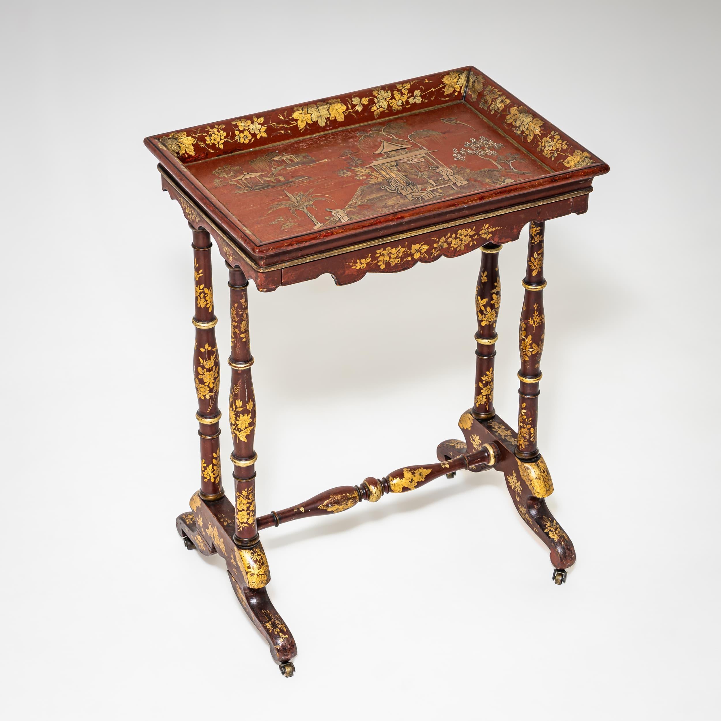 Beistelltisch mit doppelten Balustern auf gegabelten Füßen und kleinen Messingrollen. Die Tischplatte hat einen erhöhten Rand und eine einzelne Schublade innerhalb der geformten Schürze. Mit rotem Lack überzogen und mit vergoldeten Blumenmotiven
