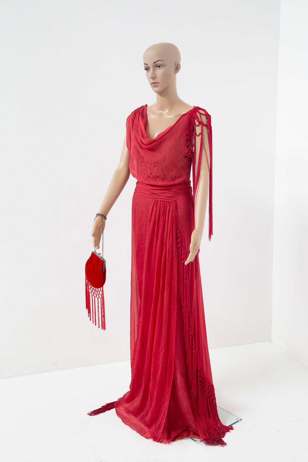 In the whispering folds of time, there is a captivating embodiment of elegance: Alberta Ferretti's sleeveless, wide-shouldered, strawberry-red silk long dress from the enchanting realm of the 2000s. Like a precious secret whispered to the breeze,