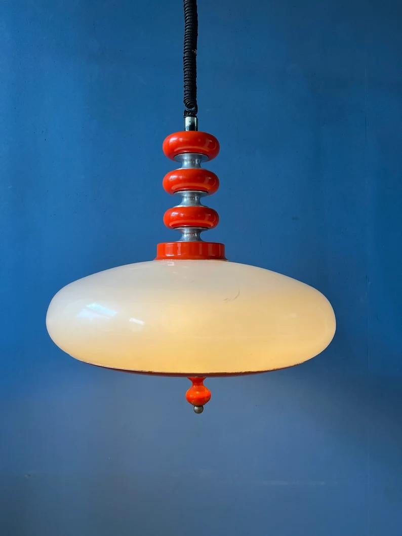Extremely rare space age pendant lamp with white acrylic glass shade and red, wooden elements. The white-red combinations give the lamp its unique feel. The height of the lamp can be easily adjusted with the rise-and-fall mechanism. The lamp