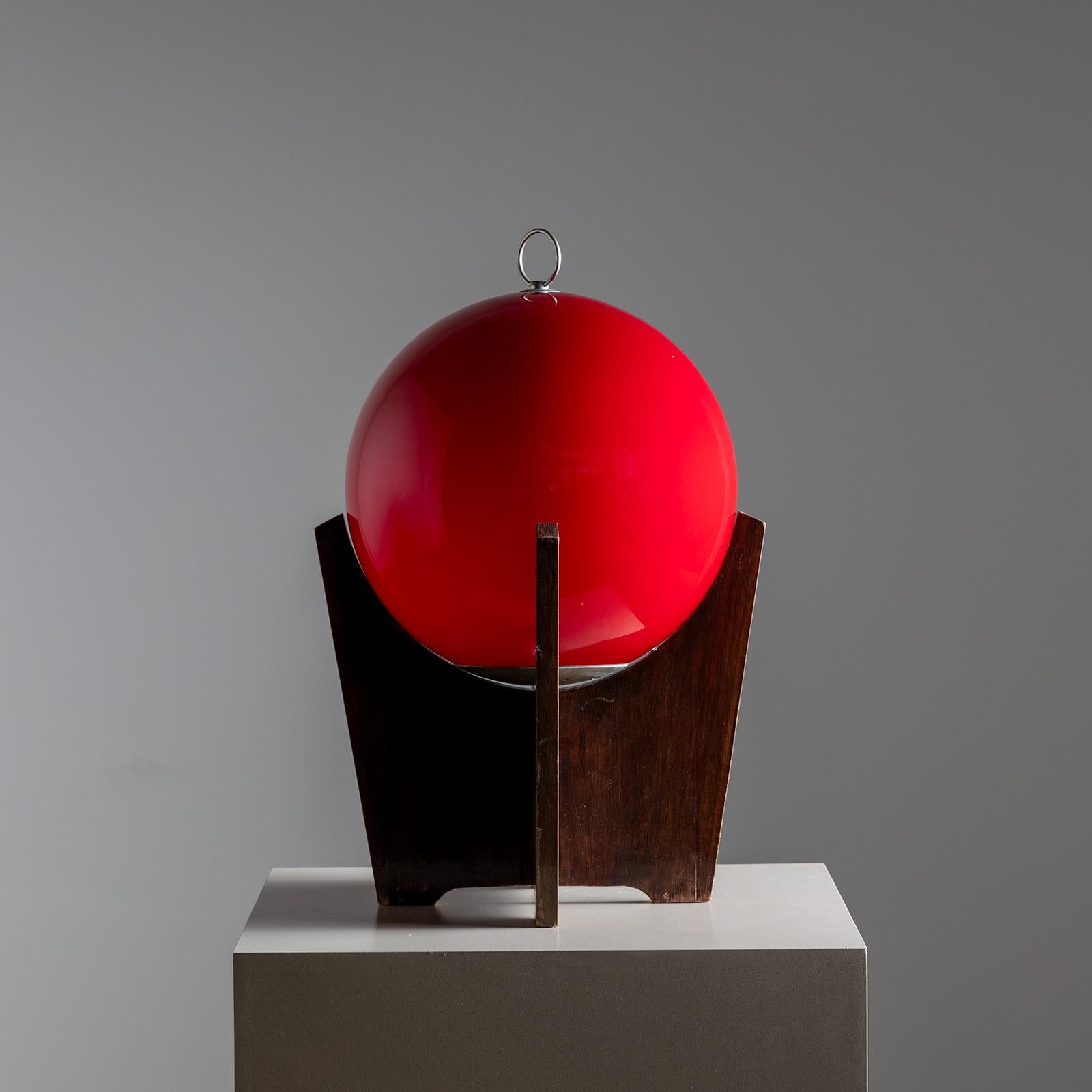 Lampe de table sur une base tripode en placage avec un abat-jour sphérique rouge avec anneau nickelé. Attribué à Luciano Vistosi, vers les années 1960.