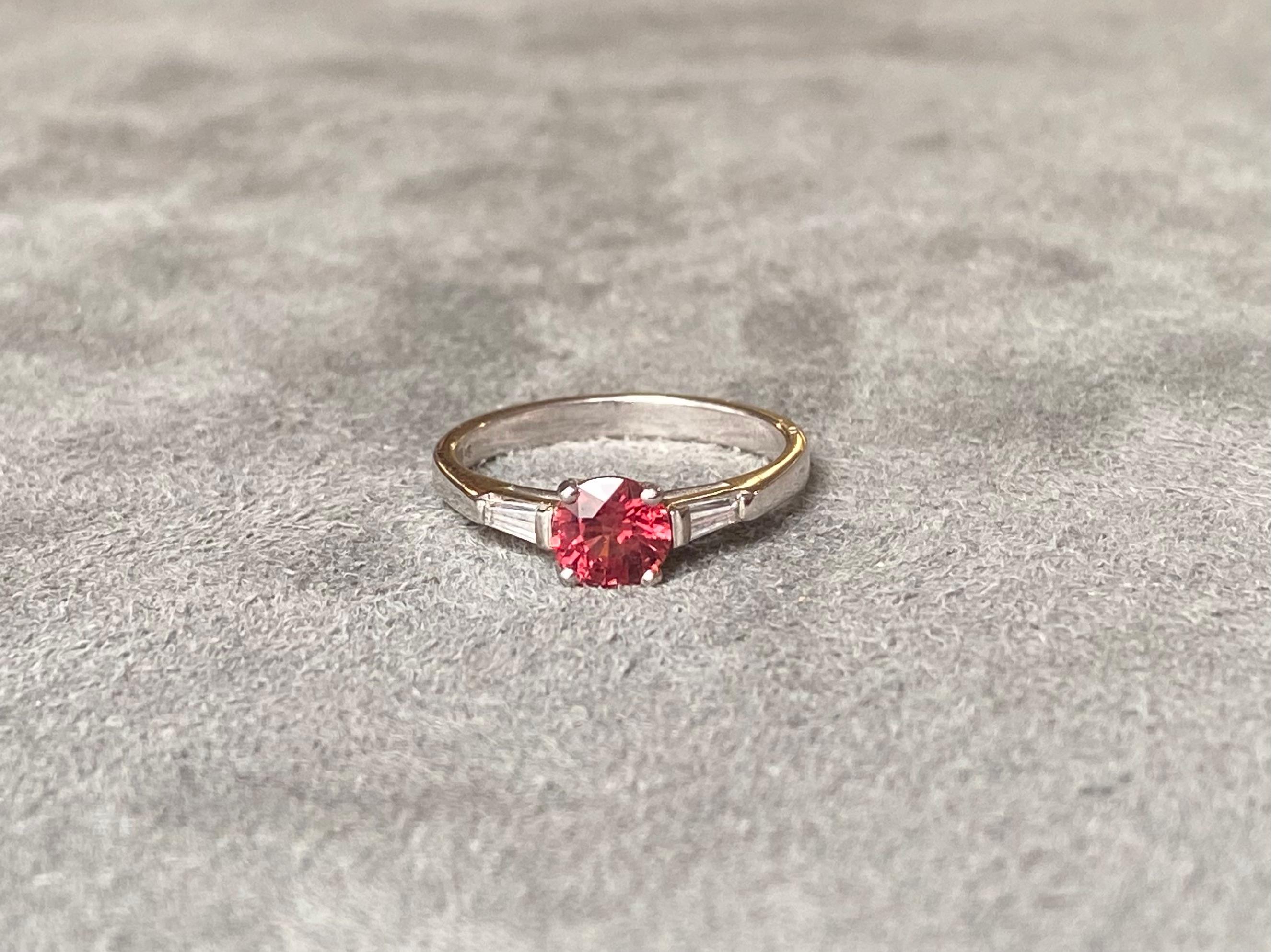 A orangy-red spinel of approximately 0.60ct set with two tapered diamonds (approximately 0.25ct total G VS) in 18k white gold. 