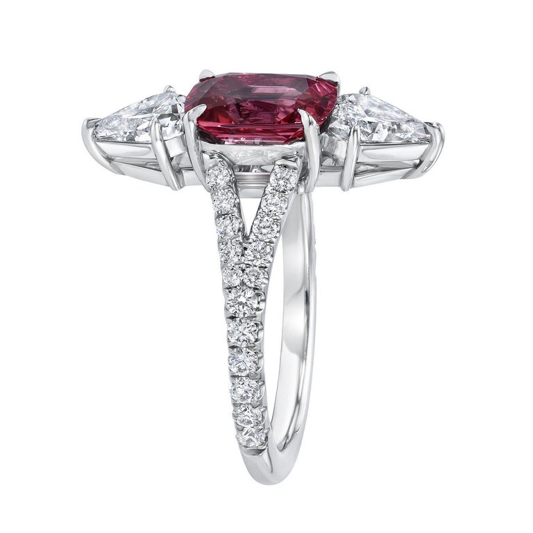 Pinkish Red Spinel cushion, weighing a total of 1.75 carats, is joined by a pair of shield shaped diamonds, E/VS2, weighing a total of 0.91 carats, and adorned by a total of 0.40 carats of round brilliant diamonds on the shank, to create this