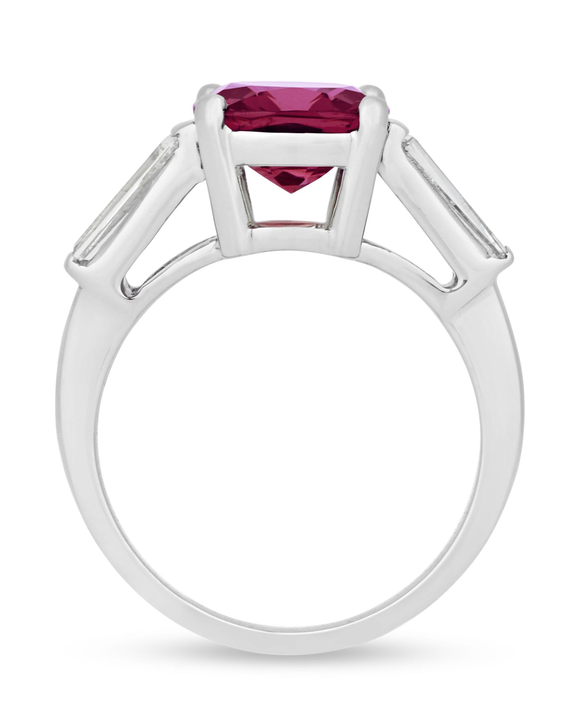 A sparkling red spinel captivates the eye in this ring. Exhibiting a deep crimson color, this 3.27-carat jewel is set in platinum between diamonds totaling 0.35 carat. Though often mistaken for rubies or sapphires, spinels have experienced a surge