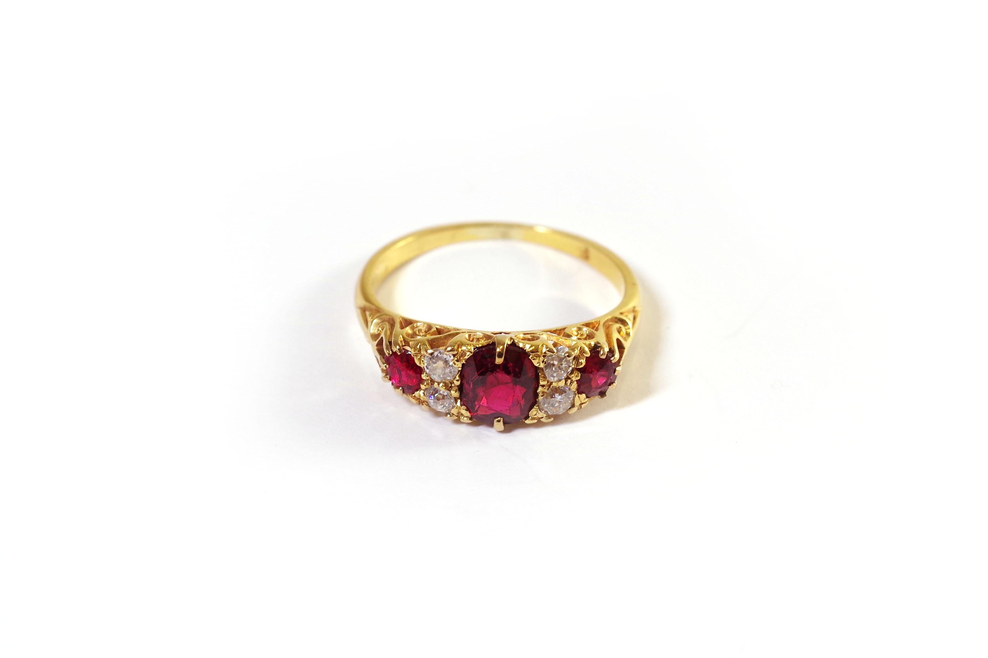 Red spinel trilogy ring 18 karat yellow gold. Three oval spinels adorn the ring, between each spinel are four old cut diamonds. The spinels have a beautiful dark red colour. The ring is finely chiselled on the gallery and shoulders, with a floral