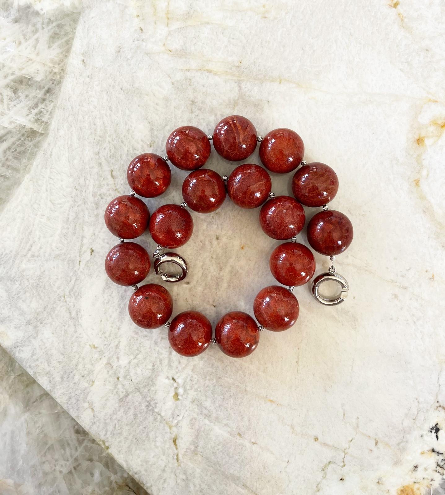 Stunning necklace comprised of 24mm natural color round red coral beads, sterling silver accent/spacer beads, and finished with an interlocking ring clasp. This necklace features a striking range of vibrant red tones. It measures approximately 20