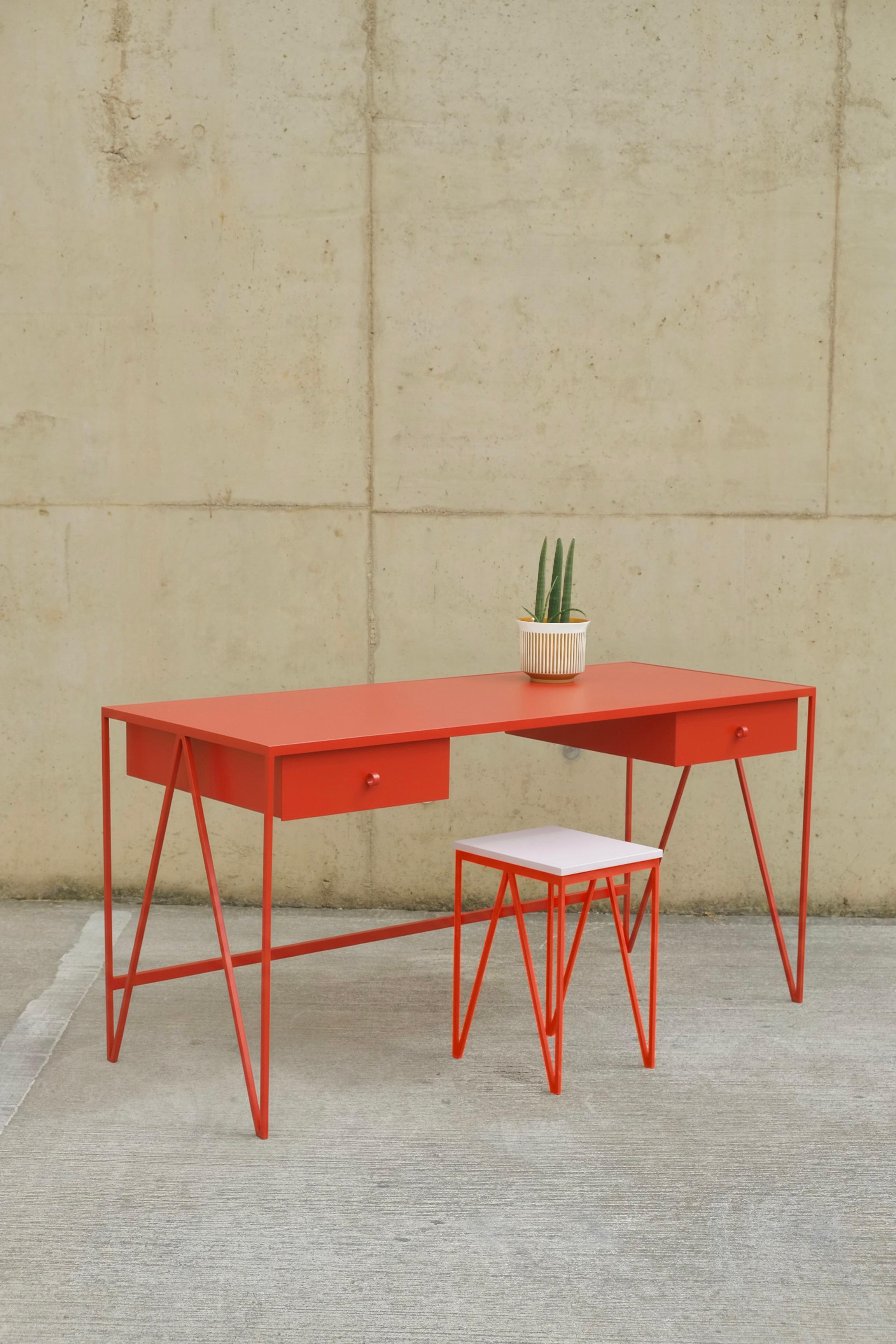 A large red study desk made with a powder coated steel frame and a beautiful lacquered plywood colour matched table top. This modern minimal desk has two steel drawers suspended underneath the tabletop with our Loop handles. The study desk looks