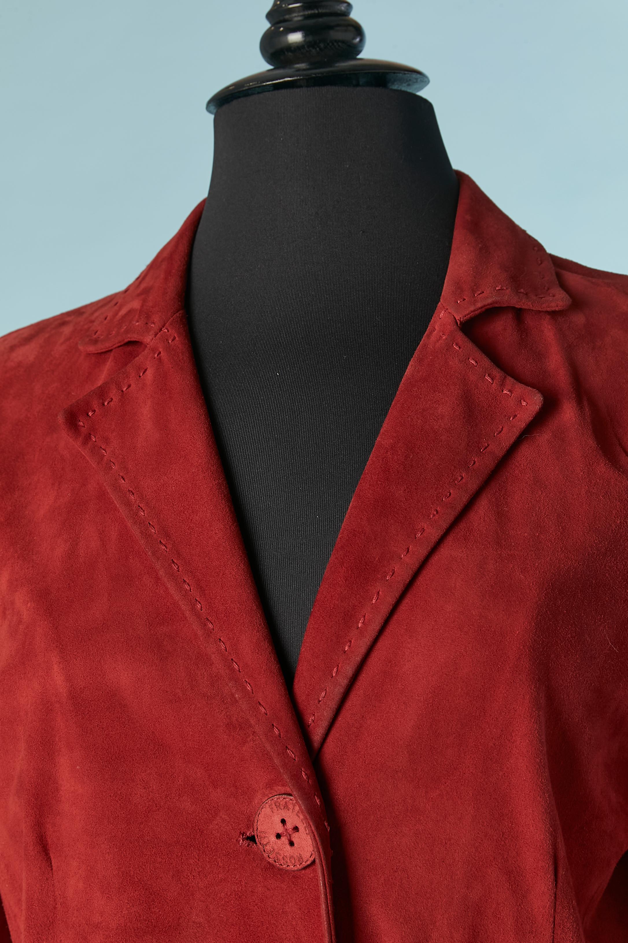 Einreihiger Mantel aus rotem Wildleder . Knöpfe aus Wildleder und Leder mit Markenzeichen. Abgesteppt, mit Schnitt und Taschen auf beiden Seiten und Baumwollfutter. Der Mantel ist nicht gefüttert.
GRÖSSE 40 / L 
