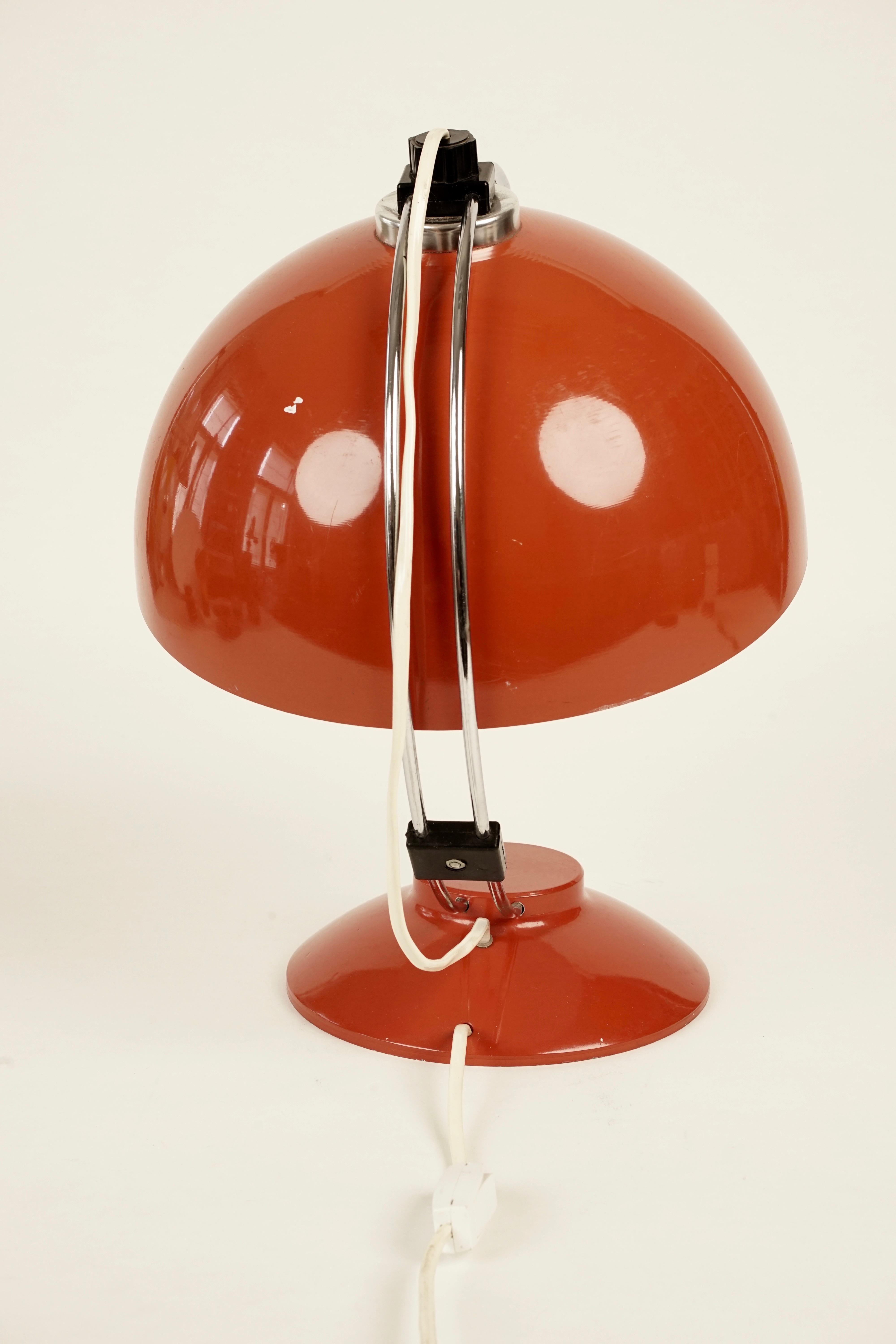 A beautiful red table lamp from the 1970s. The lamp is composed of a heavy red base with a curved chrome stem.
The shade can be adjusted by sliding it along the stem.