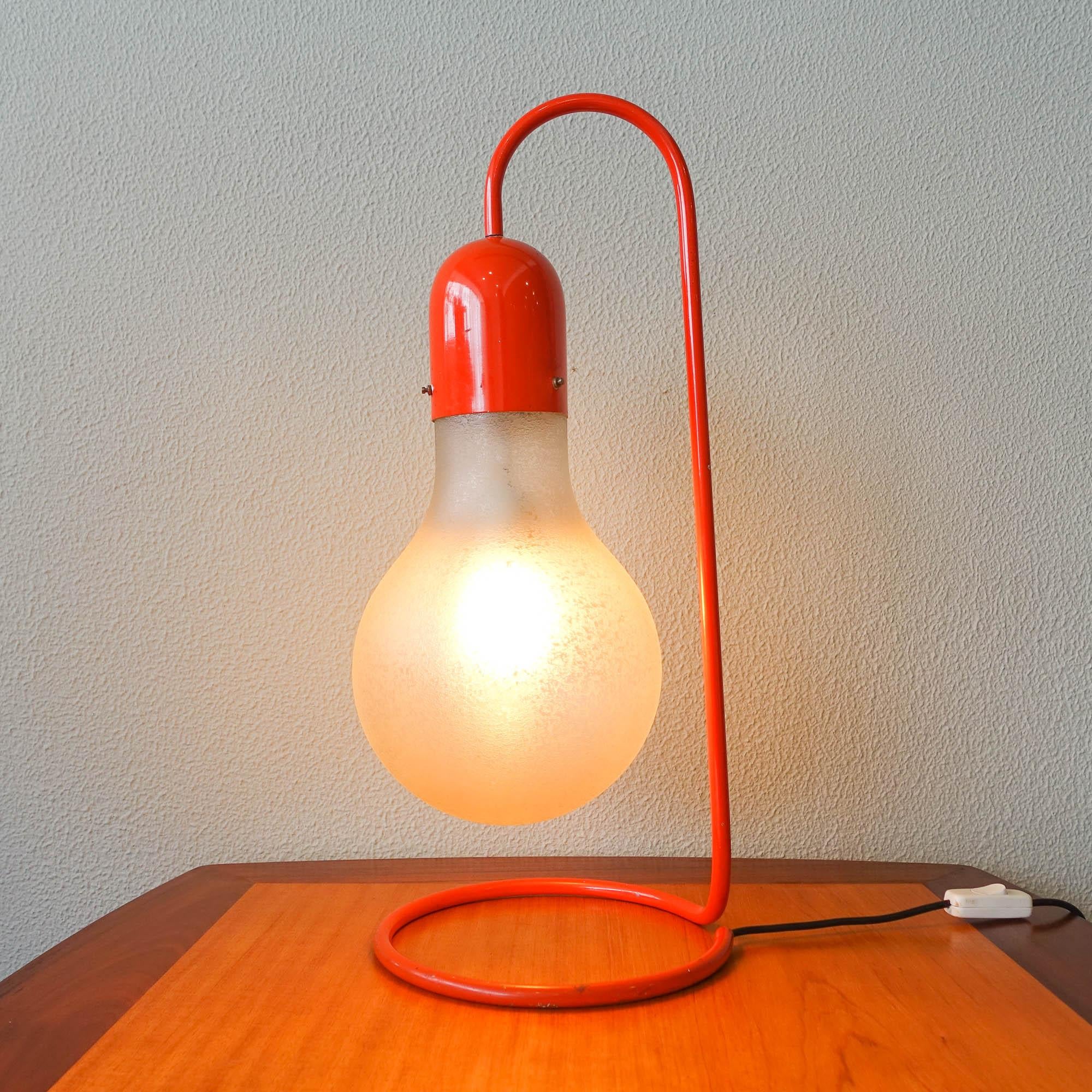 This table lamp was designed and manufactured by Stilux Milano, in Italy, during the 1970's. It features a red frame and a blown glass shade shaped as a light bulb. In original and good vintage condition.