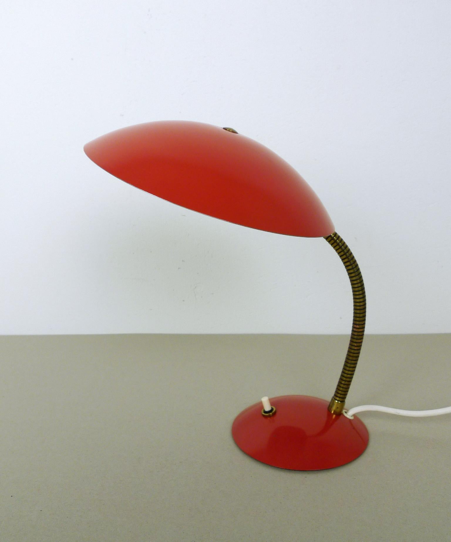 This small table lamp from the 1950s features a red lacquered shade and Stand with a brass gooseneck. It is operated by a pressure switch on the stand and has an E 14 lamp socket. The lamp is in very good condition.