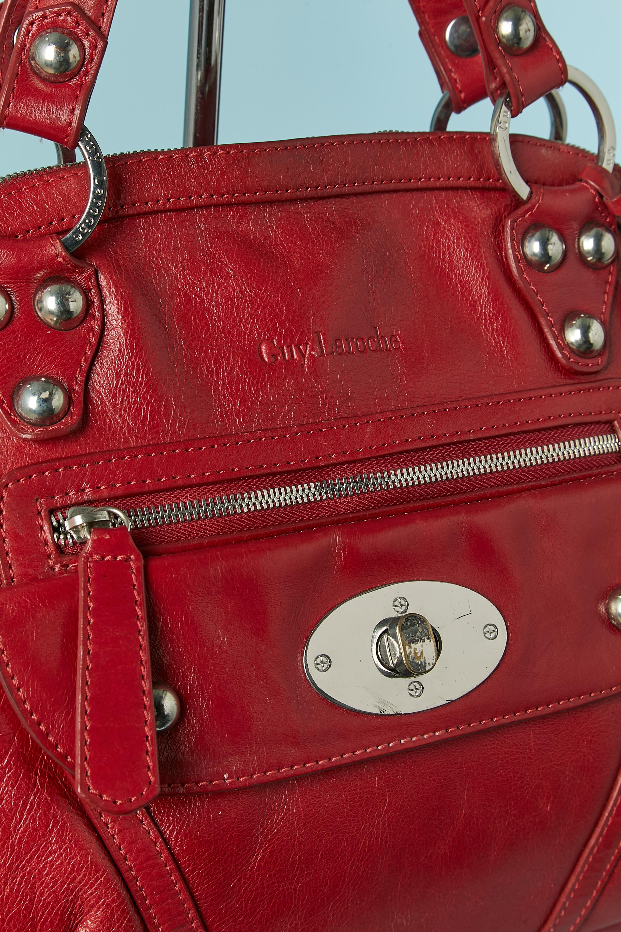 Red top handle bag with silver metal hardware and studs. Black cotton lining. 2 front pocket ( one with clasp closure, the other one with zip closure. One back pocket with zip closure. One inside pocket with zip closure and 2 flat pockets) . 
Silver