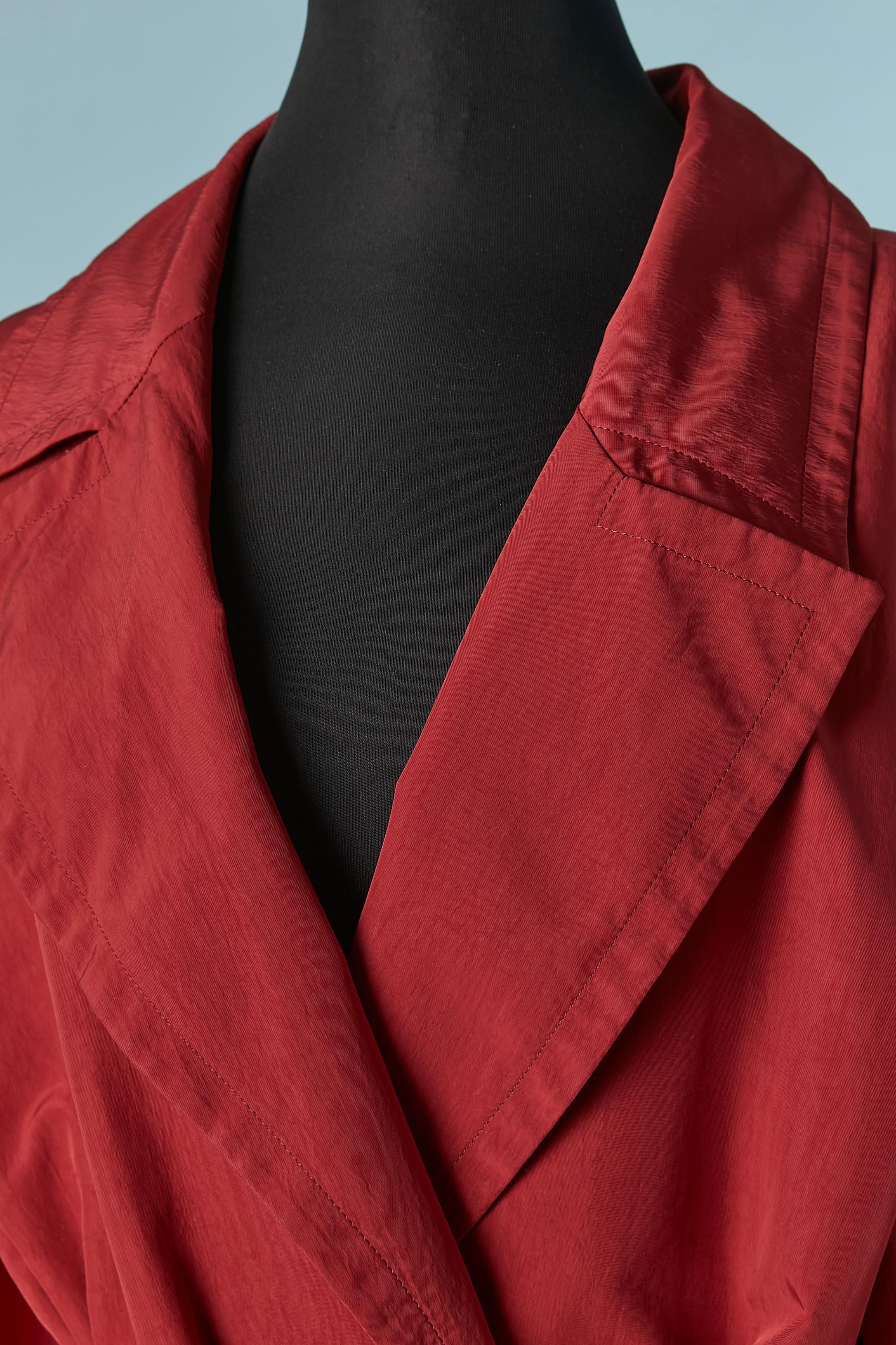 Trench rosso con cintura. Non c'è l'etichetta della composizione del tessuto, ma probabilmente il tessuto principale è in nylon o poliestere e la fodera in raso. 
Cintura e passante, tasca su entrambi i lati.
TAGLIA 42 (Fr) 10 (Us) 