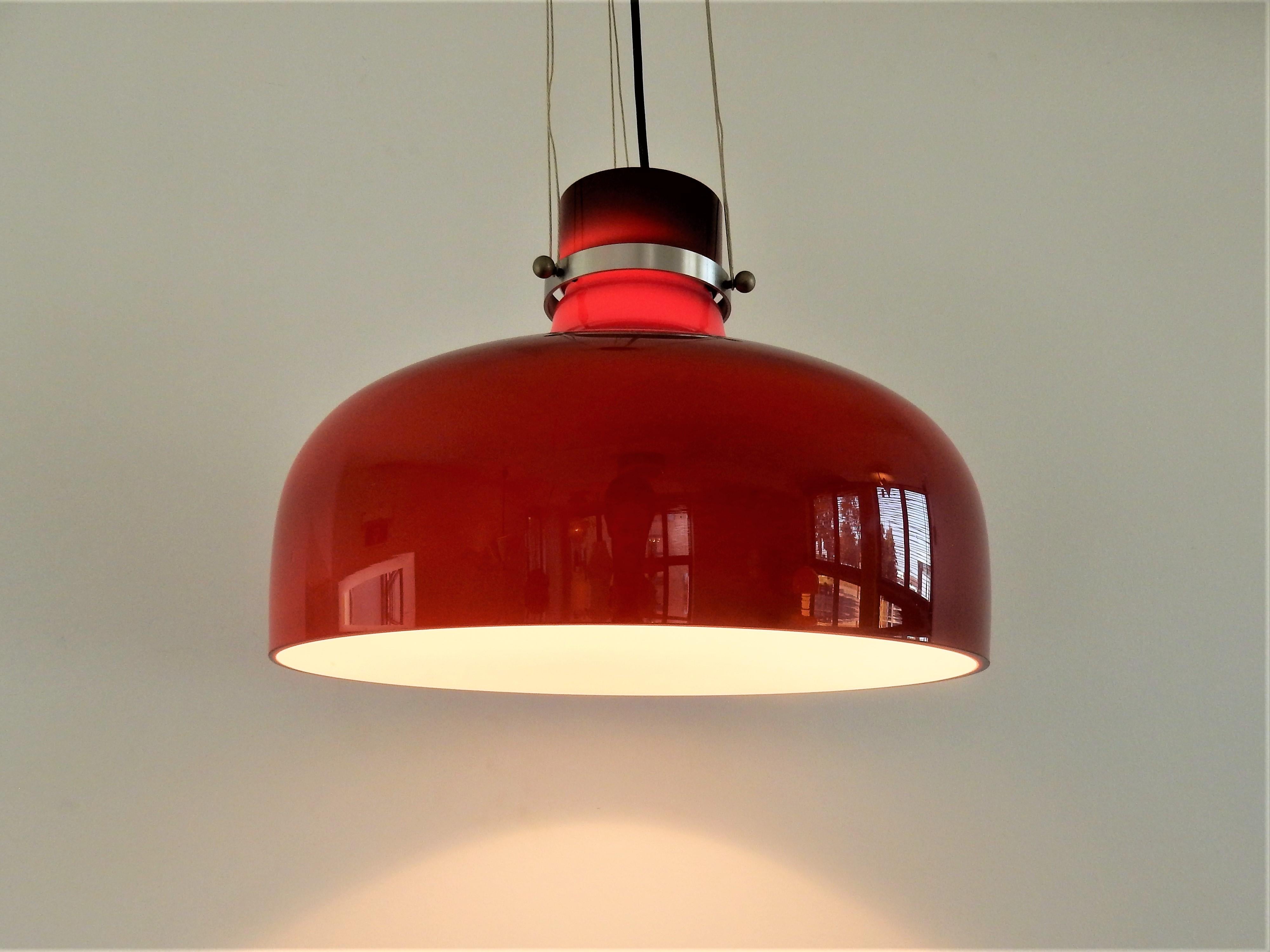 This large and very nice pendant lamp is made of red brown colored glass with a white inside. The glass is hung to the fixture by a metal ring with 3 connecting screws. This model is documented in the catalogue of Indoor, but than as a smaller size.