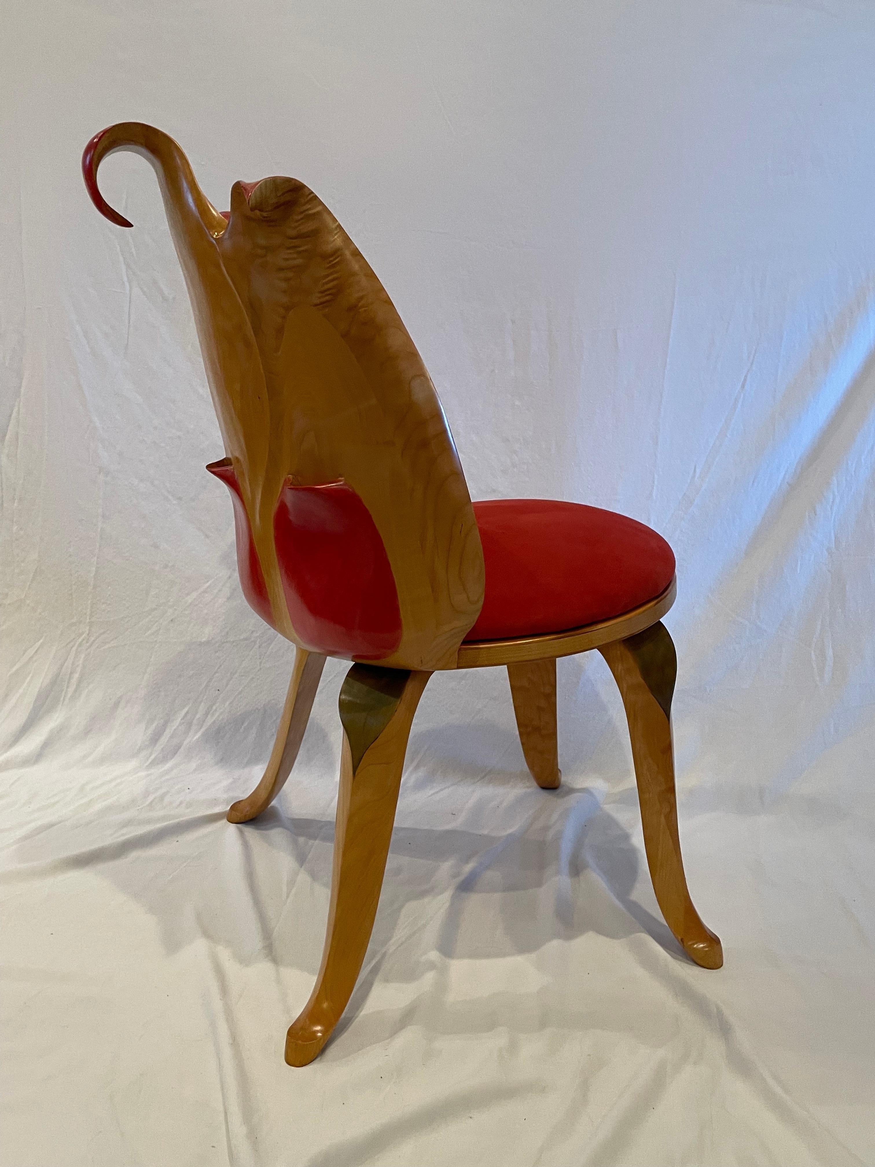 The delicate tulip shaped chair has a back that forms the inside of a tulip.
The legs are formed in leaf shapes, and the seat is finished in a luxe Ultra-suede. The back of the chair is in a natural finish allowing the beauty of the wood grain to
