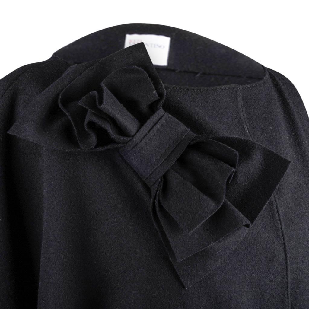 Guaranteed authentic RED VALENTINO jet black knee length coat.
Fabulously chic with draped 3/4 dolman sleeve.
Narrow, straight cut with boat neck.
Striking bow on right.
2 subtle hard to notice patch pockets.
3 over sized hidden snaps.
Fabric