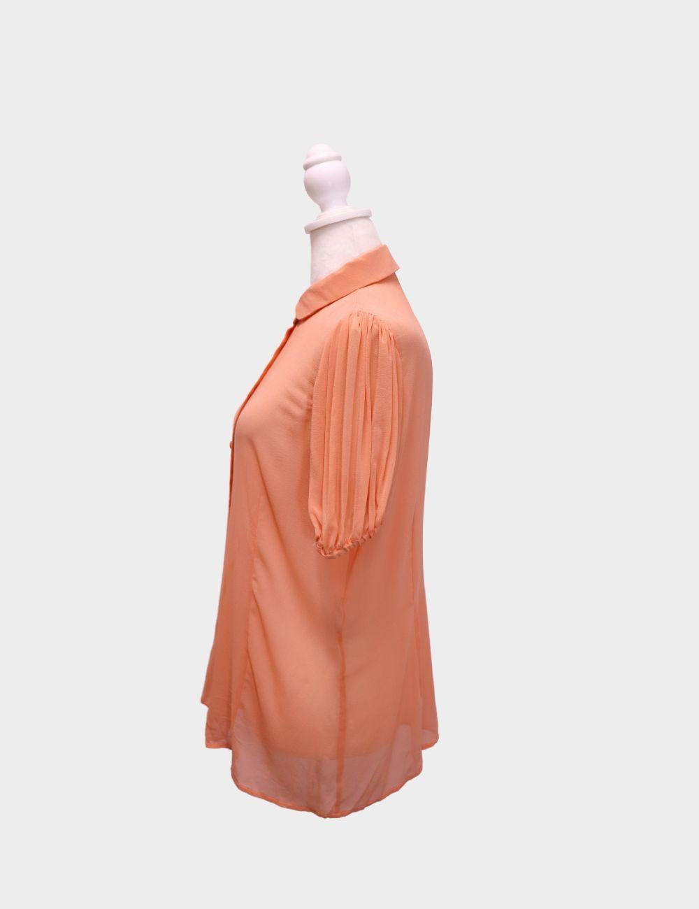 Verleihen Sie Ihrer Garderobe einen Hauch von femininem Charme mit dieser pfirsichfarbenen Bluse von Red Valentino. Dieses Button-Down-Oberteil aus leichtem, hochwertigem Stoff verfügt über einen klassischen Peter-Pan-Kragen und sanft geraffte