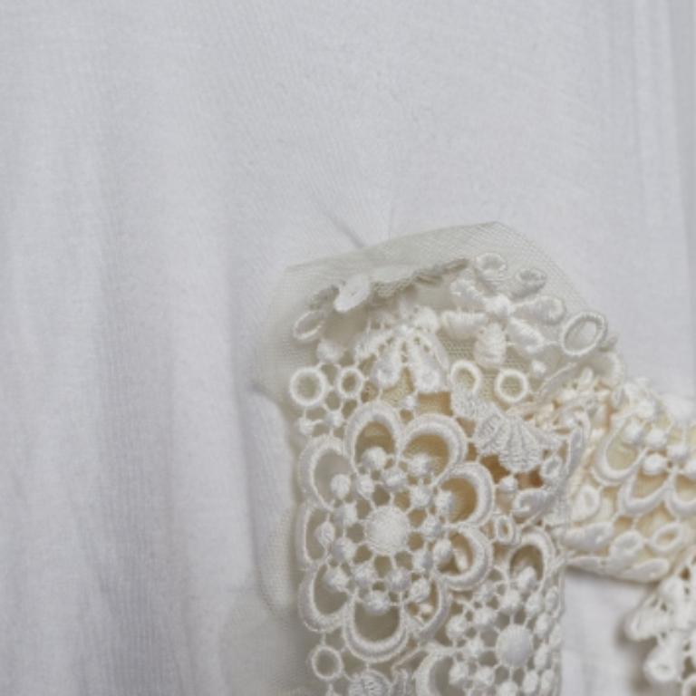 Este top de RED Valentino añadirá un toque encantador a tu atuendo informal. Está confeccionado en tejido modal blanco, con un detalle de lazo de encaje adornando la parte delantera. Este top tiene manga corta y cuello redondo.