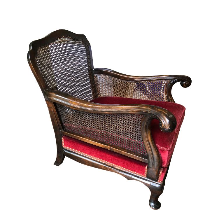 Red velvet carved wood Bergère or Charles of London Chair. In the style of Louis XIV. The chair features a rounded cane back and sides, curved arms, and cabriole legs. 

The deck is upholstered in plush red velvet. Removable cushion in the same.