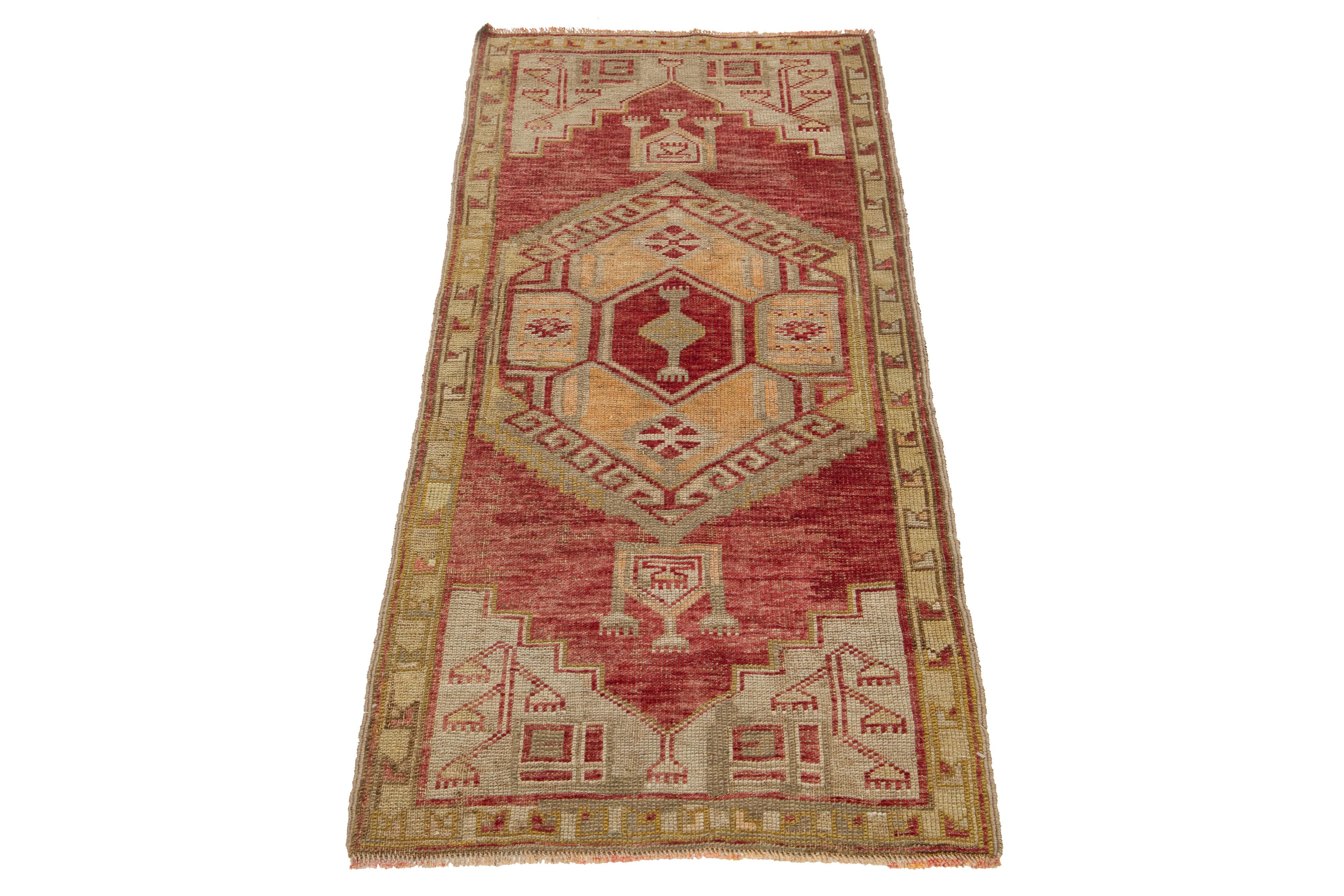 Beautiful vintage Anatolian hand-knotted wool rug featuring a red color field. This piece showcases beige, brown, and peach accents within a stunning geometric tribal design.

This rug measures 2'3