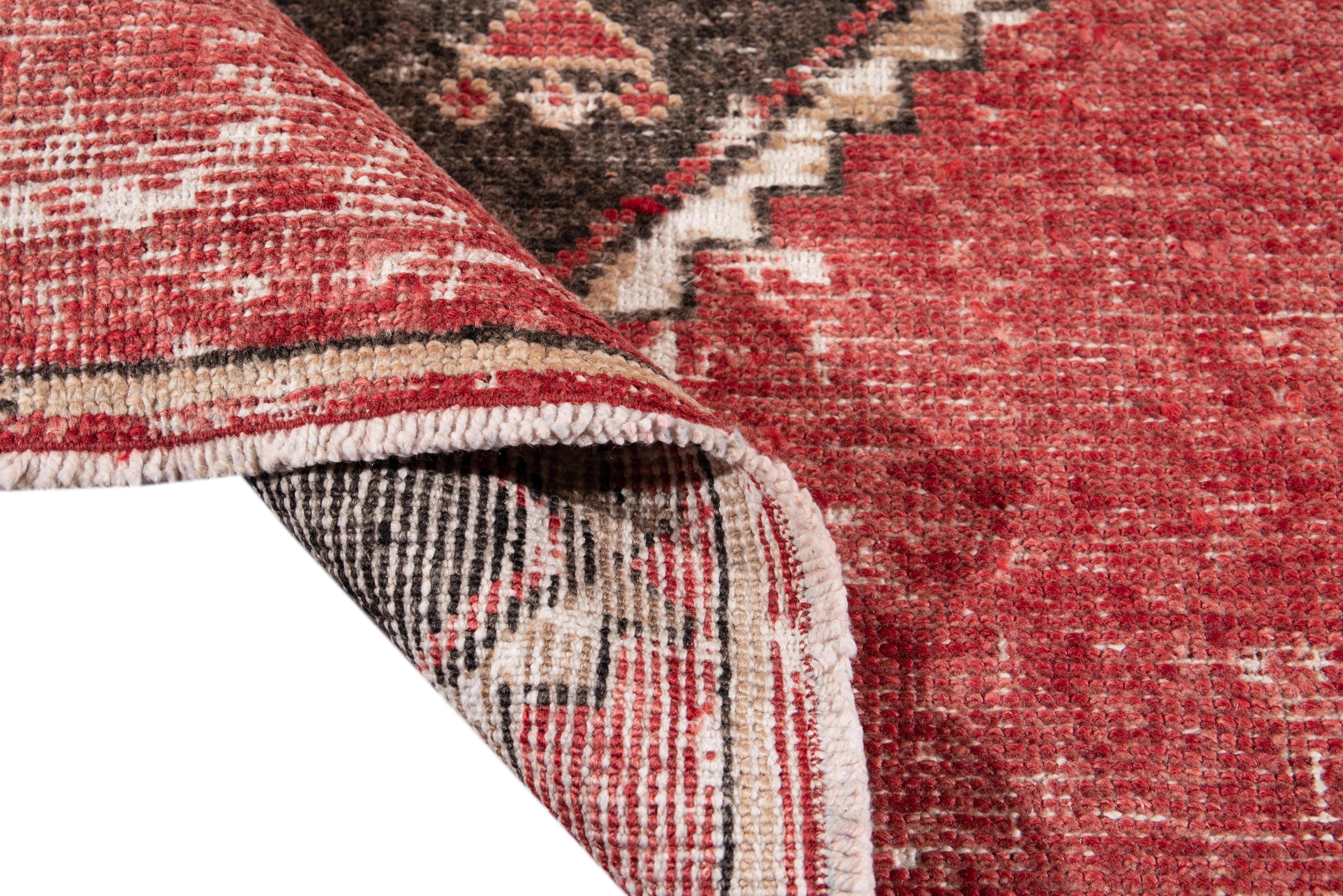 Beautiful vintage Turkish hand knotted wool rug with a red field. This rug has accents of brown and beige in a gorgeous all-over geometric design,

This rug measures: 3'1