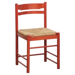 Chaise vintage rouge en bois des années 1970 avec une assise en osier tressé.