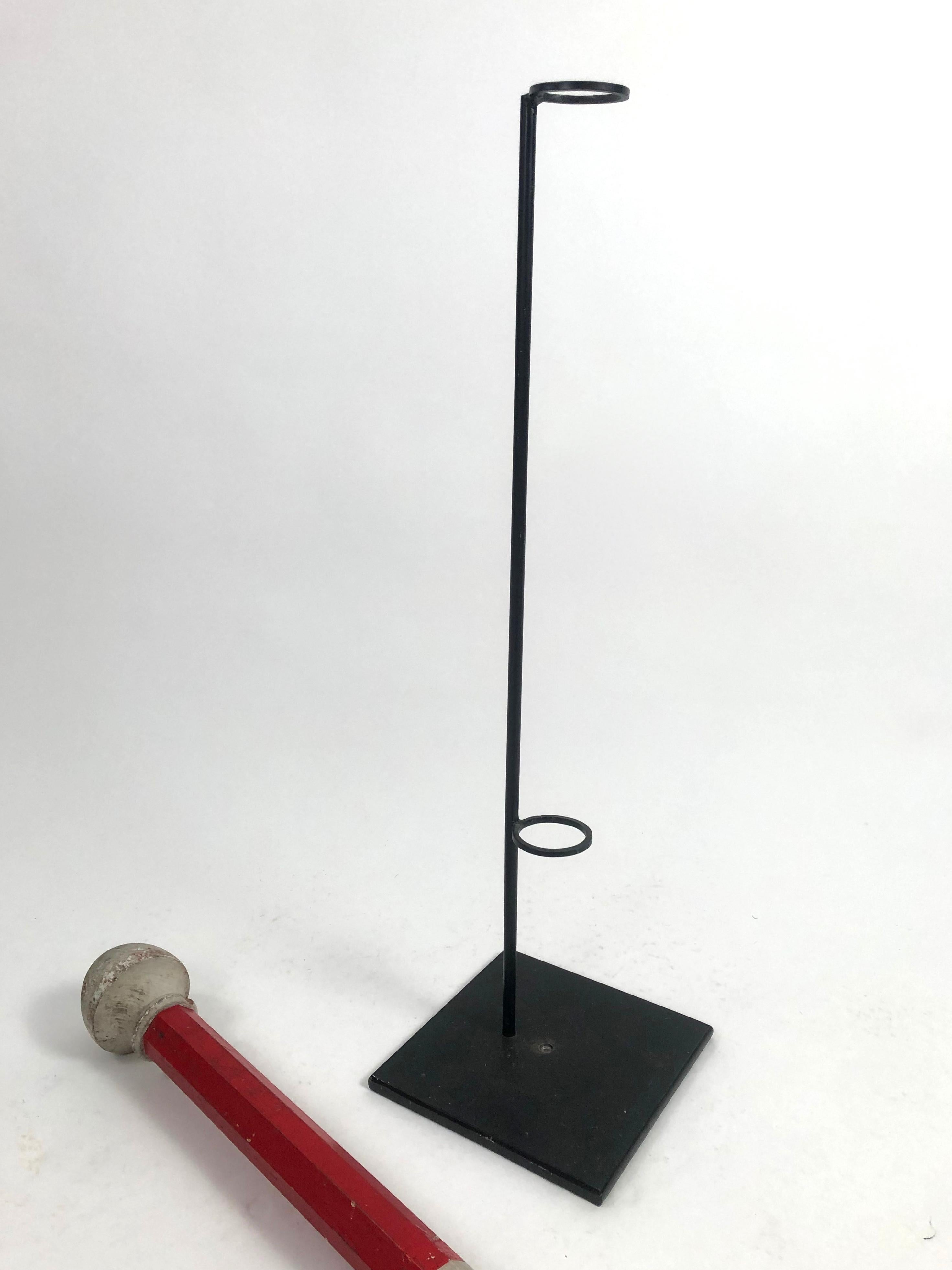 A tall red, white and blue carved and painted patriotic wood staff used in parades, on a custom made black painted metal display stand.
