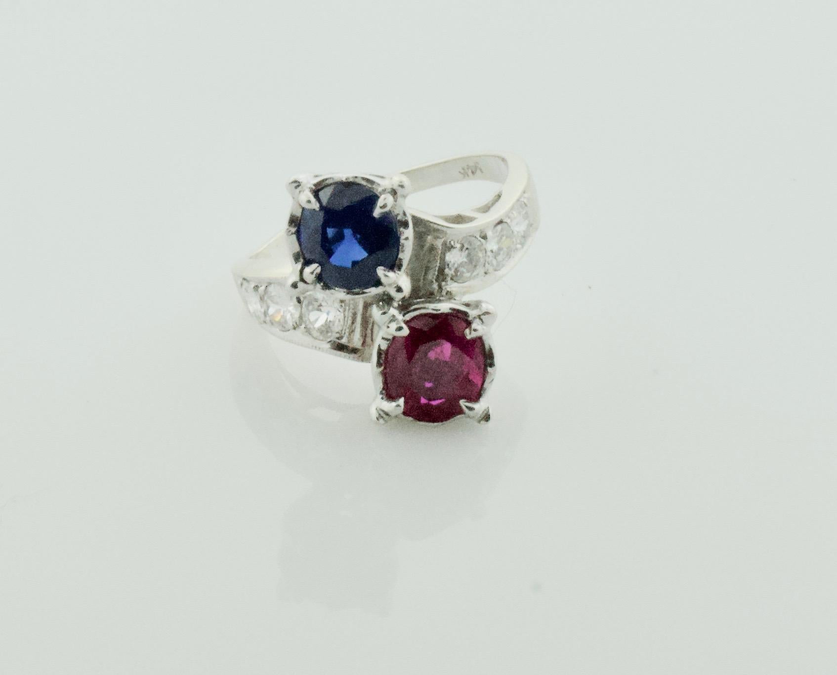 Red, White and Blue Sapphire, Ruby and Diamond Ring in White Gold Circa 1940's
This Classic Crossover Design Features:
One Oval Ruby Weighing 1.53 Carats  [bright with no imperfections visible to the naked eye]
One Oval Sapphire Weighing 1.43 Carats