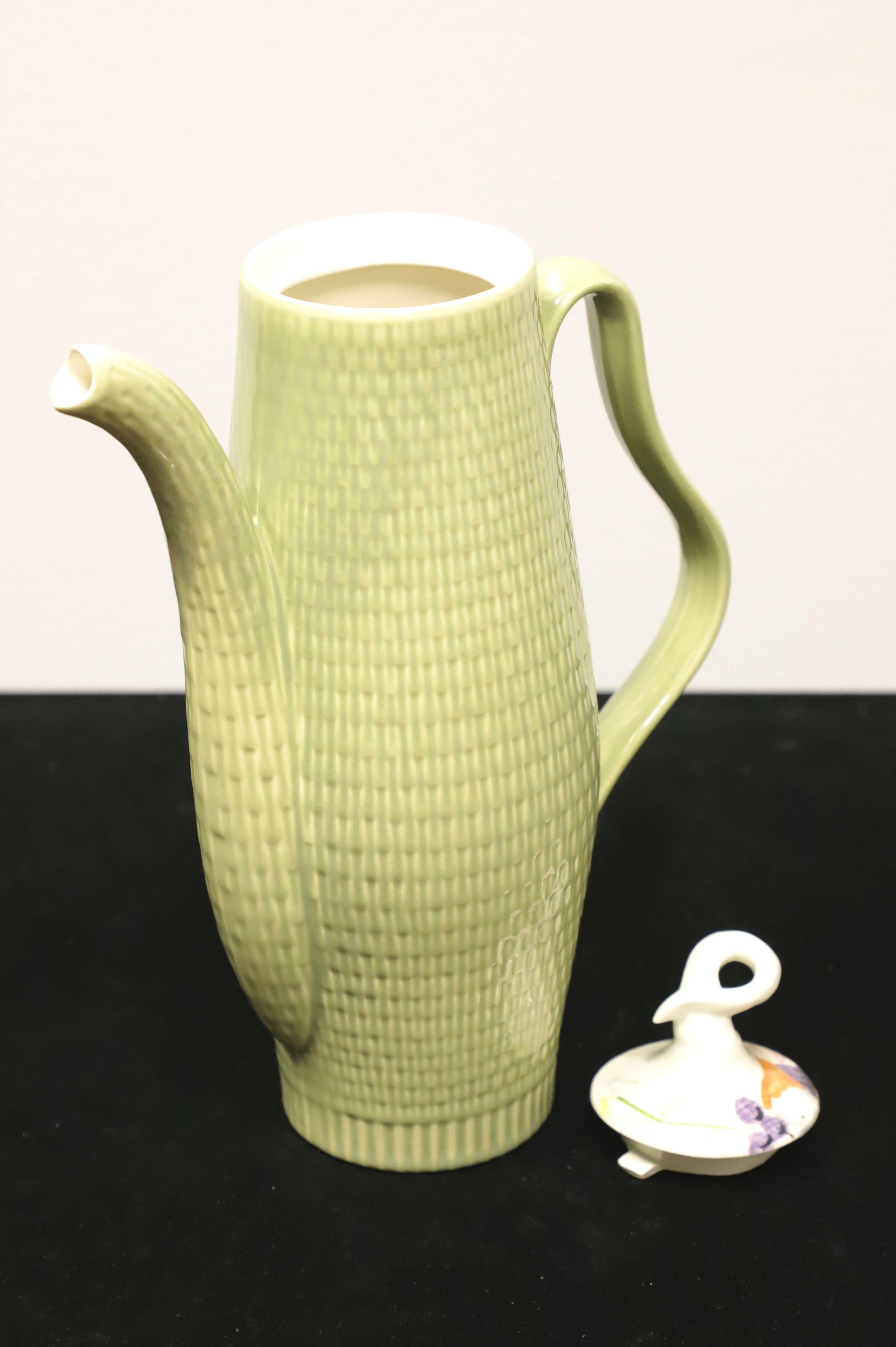 A Mid 20th Century coffee pot with lid by red wing, in their Capistrano pattern. Pot has a tall cylindrical shape, smooth cream color interior and sage green color basket weave exterior, pour spout & handle. Lid has a unique curled stem-like handle