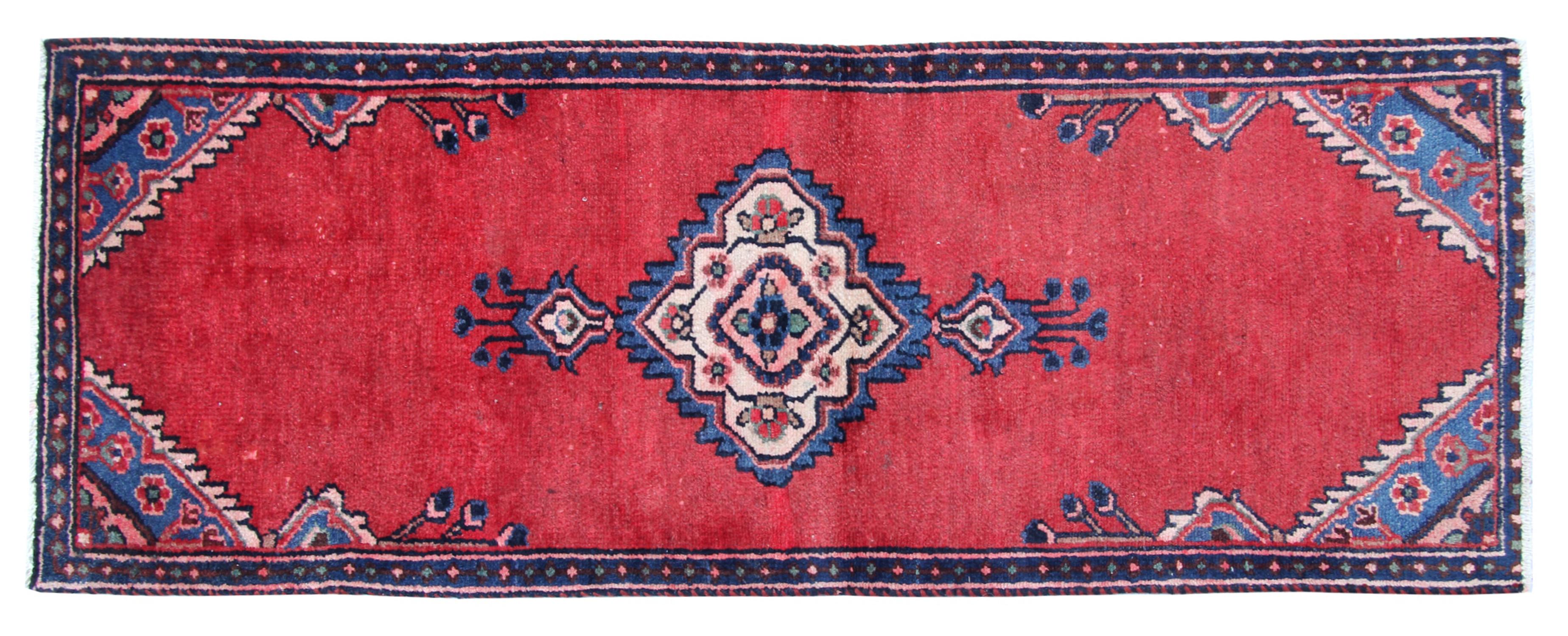 This truly unique area rug has been hand-woven with a highly-detailed symmetrical, tribal motif design, with a simple red cream colour palette. Featuring simple medallion design woven intricately on a rich red background with blue and ivory accent