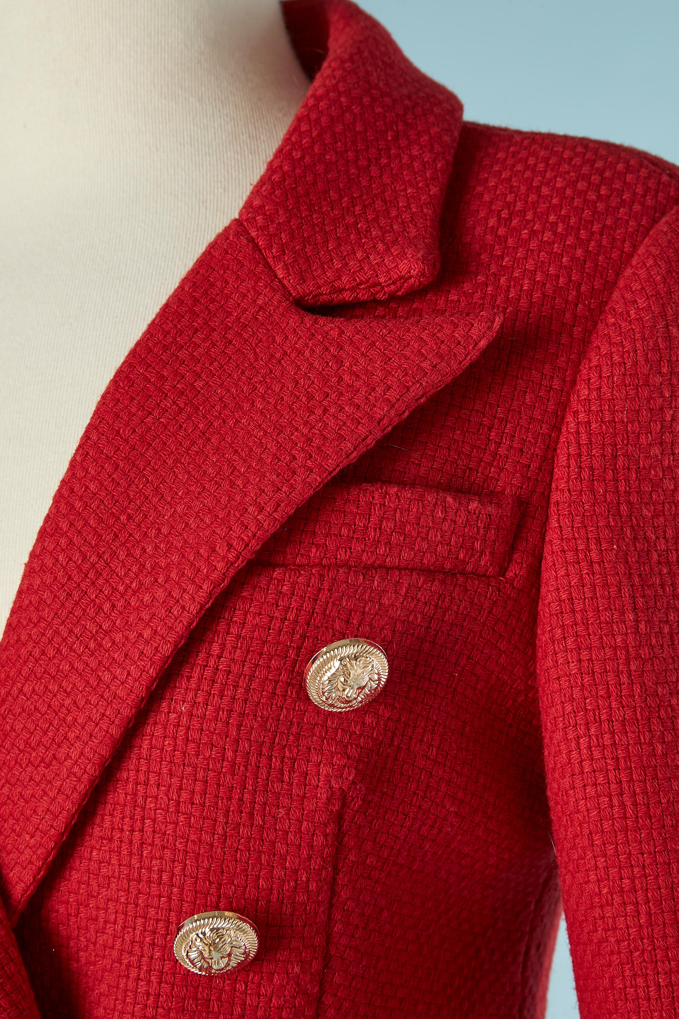Tailleur jupe en laine rouge avec veste à double boutonnage et poches sur les deux côtés. Pad d'épaule. Il n'y a pas d'étiquette de composition du tissu mais le tissu de la coquille est probablement de la laine et la doublure de la rayonne. Boutons
